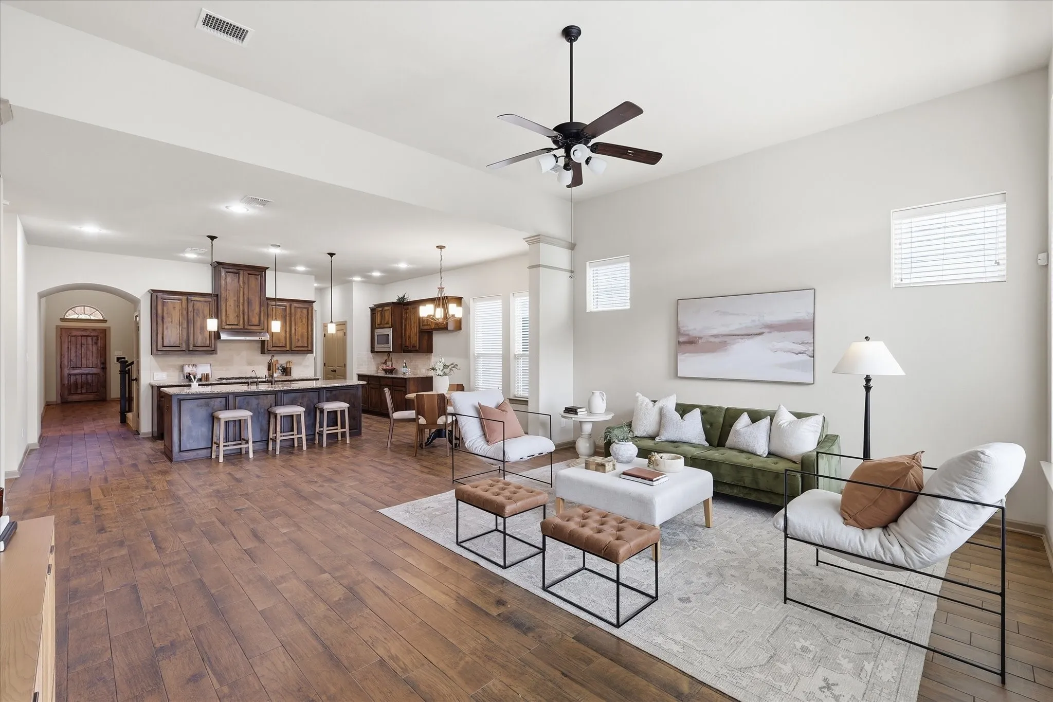 Expansive open-concept living area featuring wood-like tile flooring, high ceilings with a ceiling fan, and recessed lighting