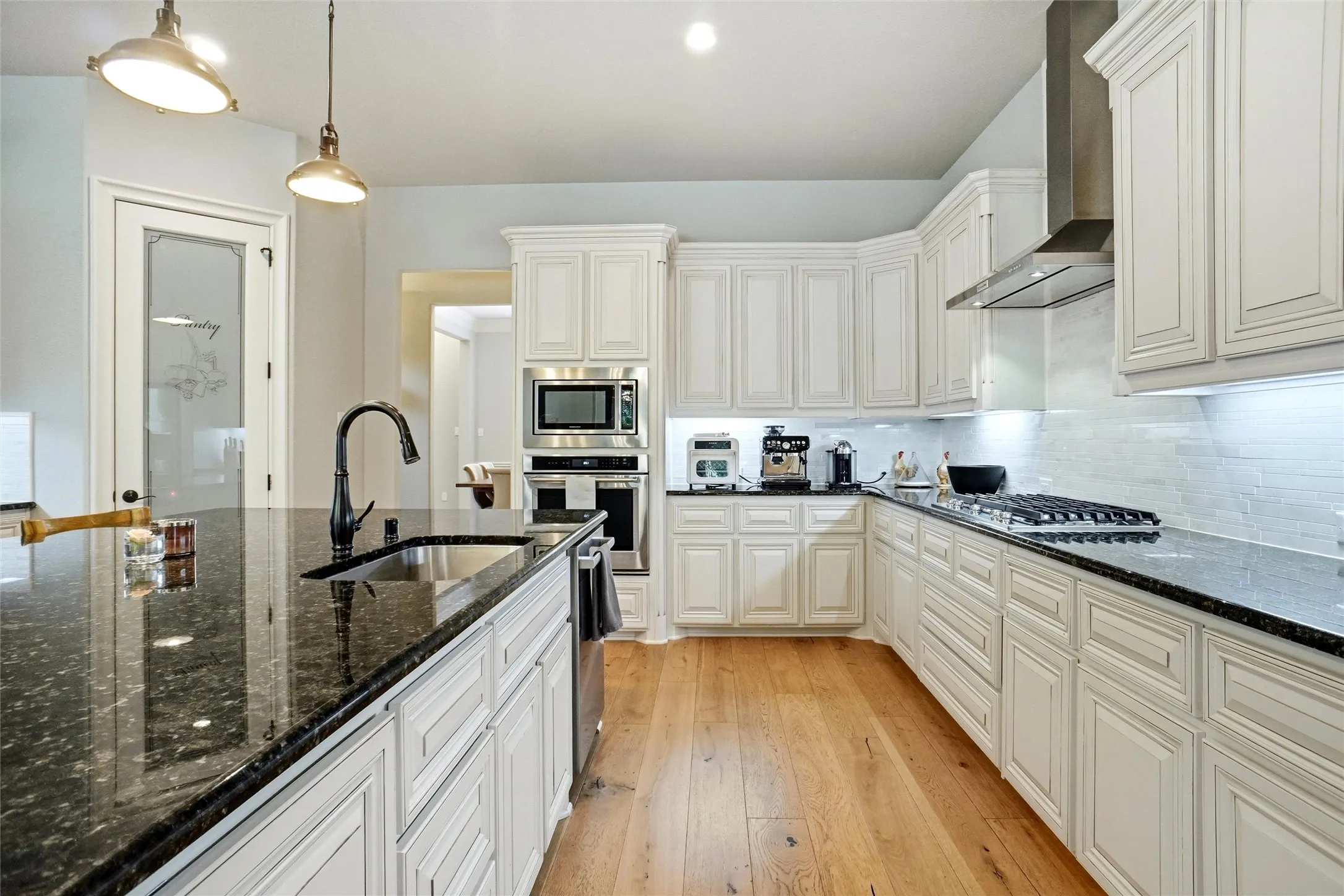 Kitchen featuring white cabinetry, dark stone countertops, stainless steel appliances, a gas range, and wood-finish flooring