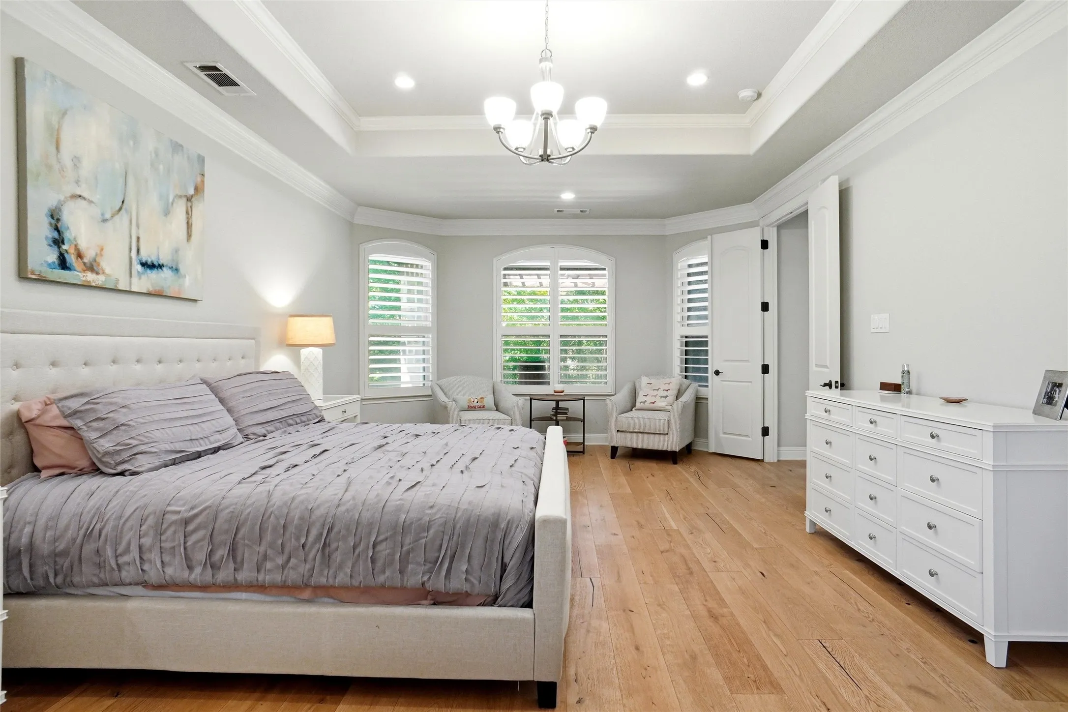 Spacious room featuring wood-finish flooring and a tray ceiling with crown molding