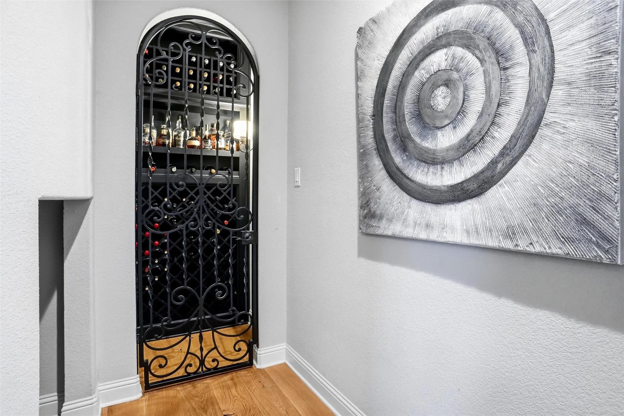 Arched entryway to a dedicated wine cellar featuring a wrought iron gate with intricate scrollwork