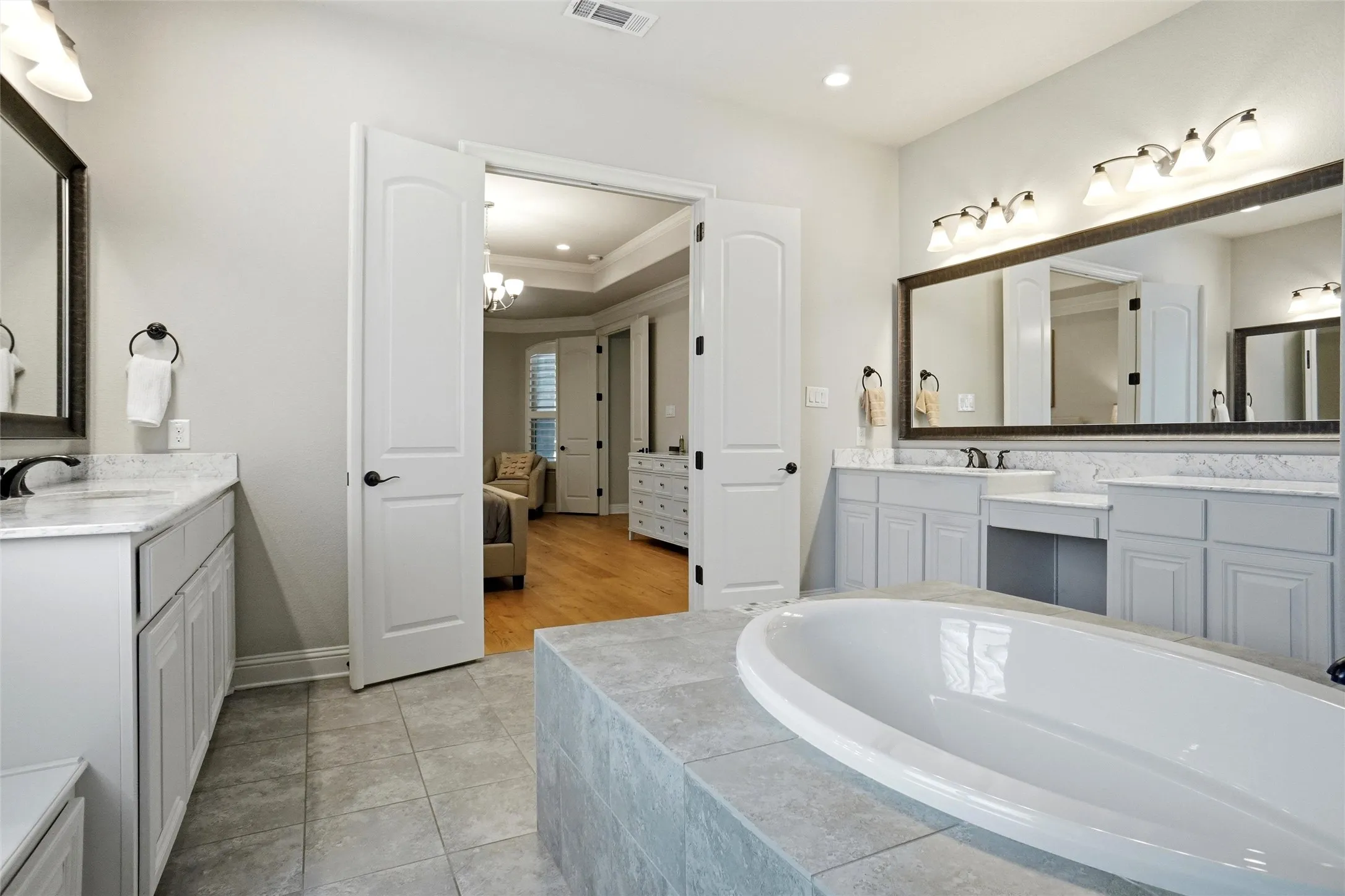 Bathroom featuring a tiled soaking tub and dual vanities with undermount sinks