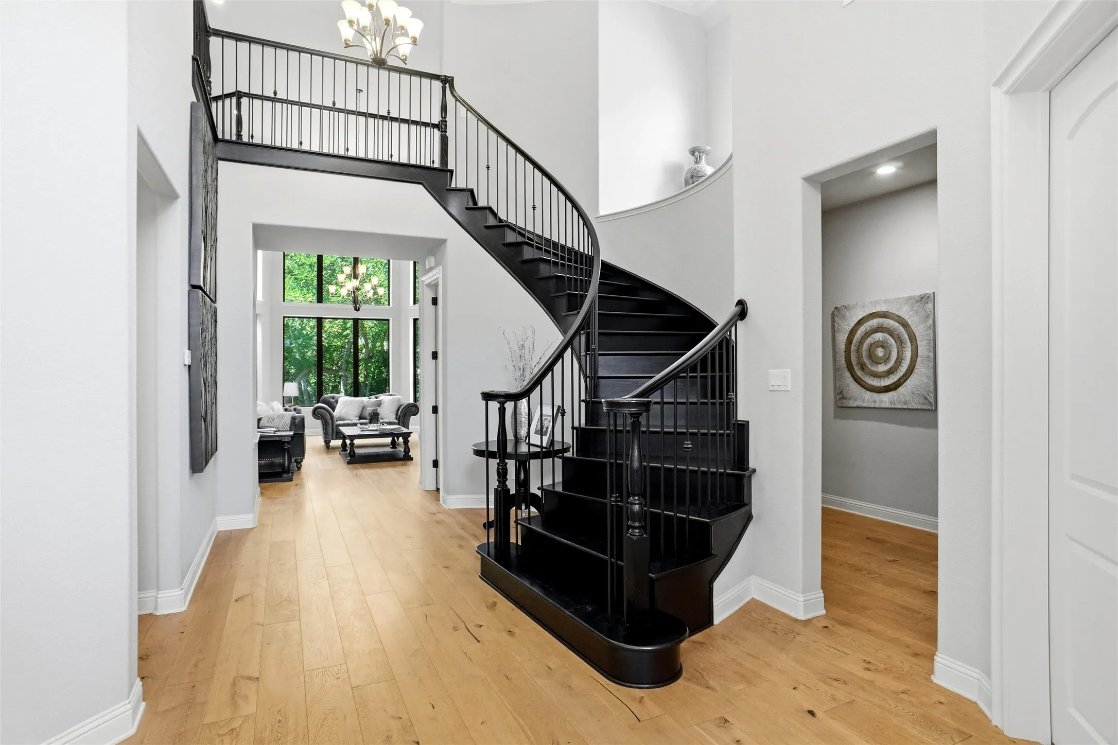 Grand foyer featuring a curved black staircase with decorative balusters and wood-finish flooring