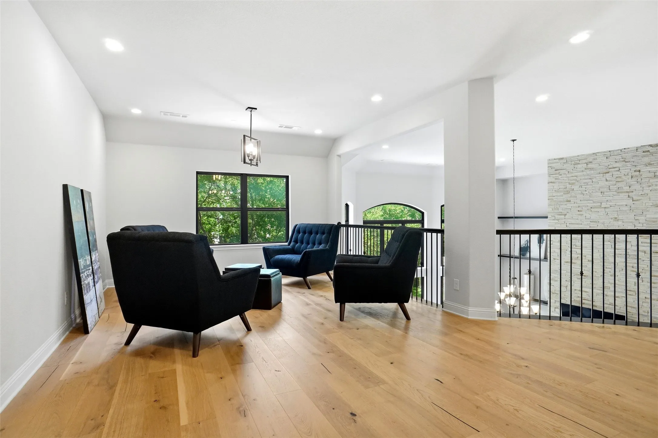 Spacious open-concept upper level featuring light wood-finish flooring, recessed lighting, and a modern pendant light fixture