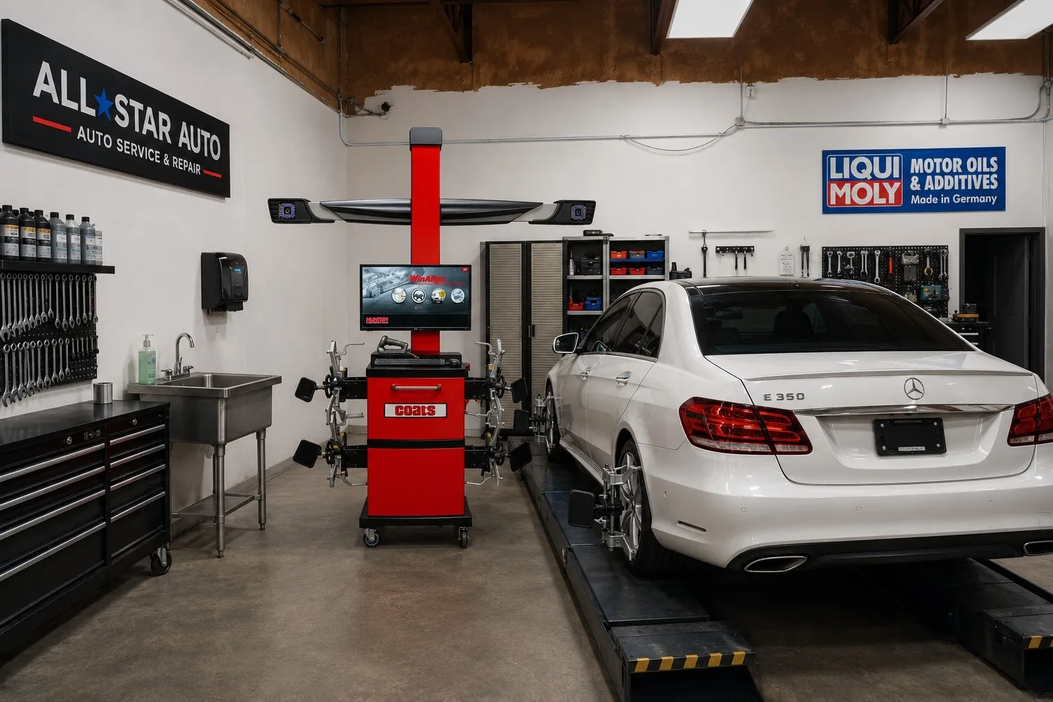 Commercial auto service bay featuring a concrete floor, a stainless steel utility sink, built-in tool storage, and an automotive lift​​‌​​​​‌​​‌‌​‌‌​​​‌‌​‌​‌​‌​​​‌​​ system