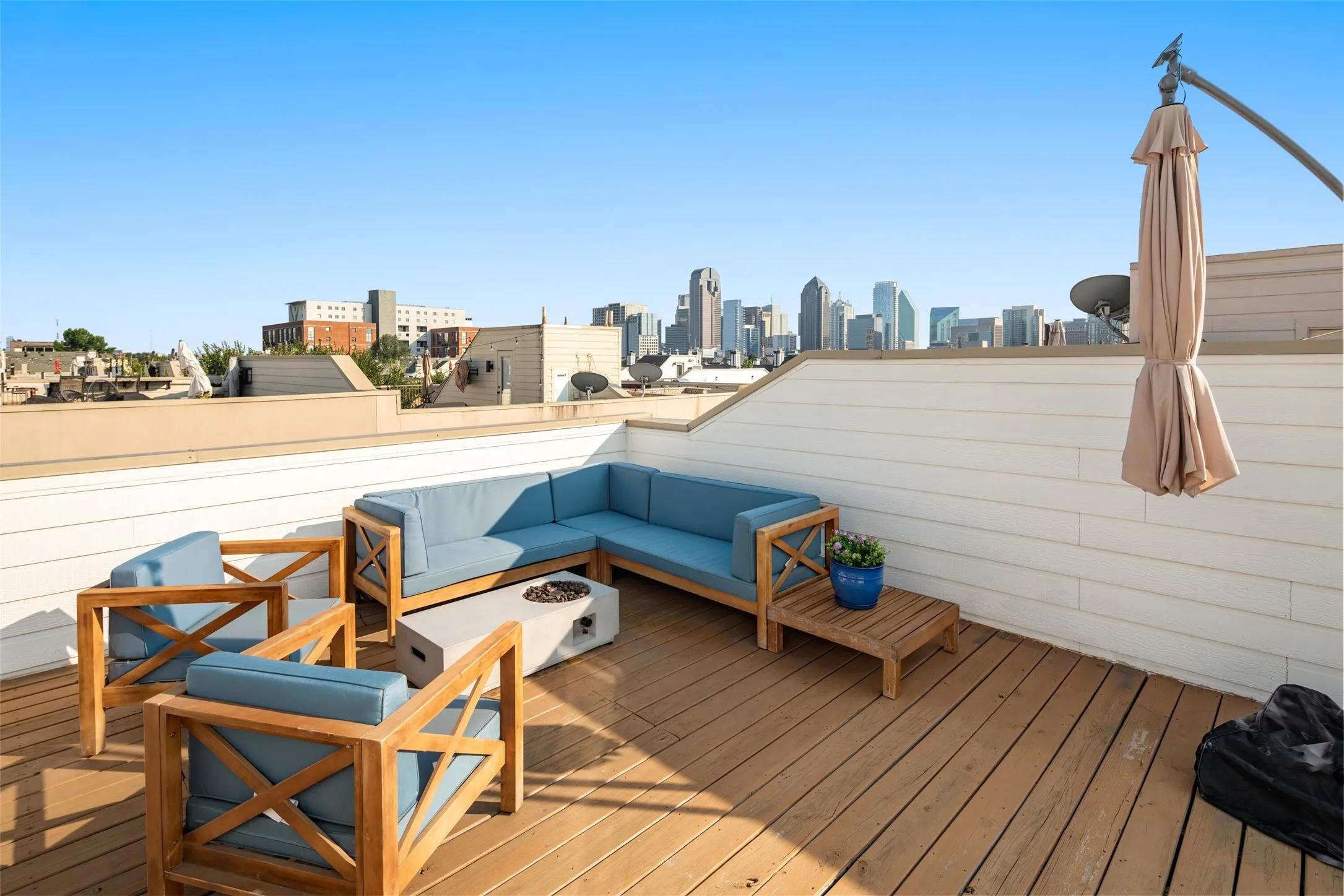 Rooftop deck featuring wood flooring, white siding, and a partial cityscape background