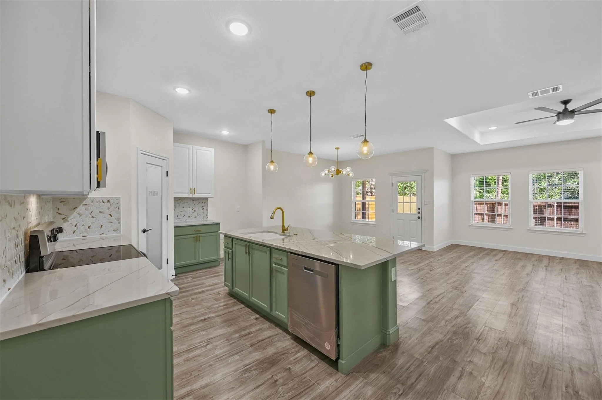 Kitchen island featuring a sink, integrated dishwasher, and pendant lighting