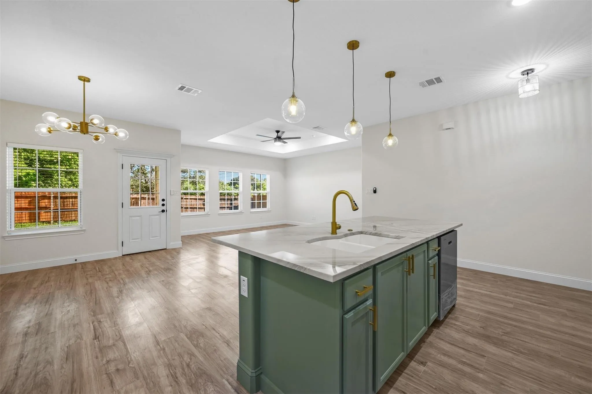 Kitchen island featuring a white countertop with integrated sink, brass faucet, and green cabinetry