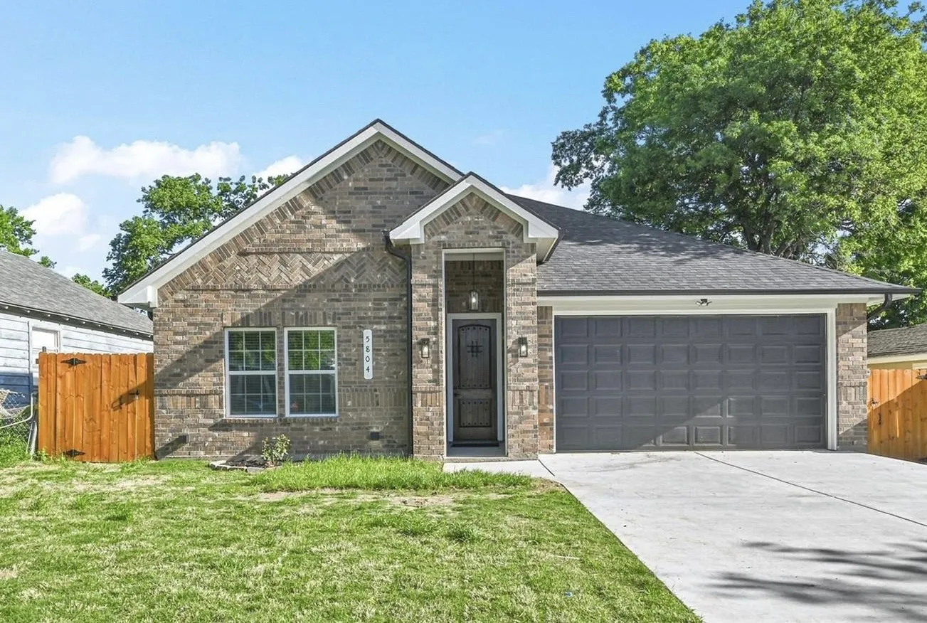 Brick exterior featuring a gabled roofline, an attached two-car garage, a concrete driveway, a covered entry, and a wood privacy fence