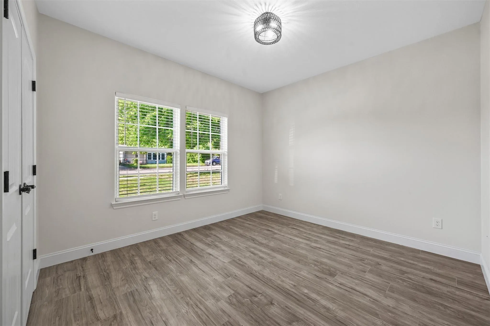 Neutral wall finishes, wood-finish flooring, and a modern ceiling light fixture