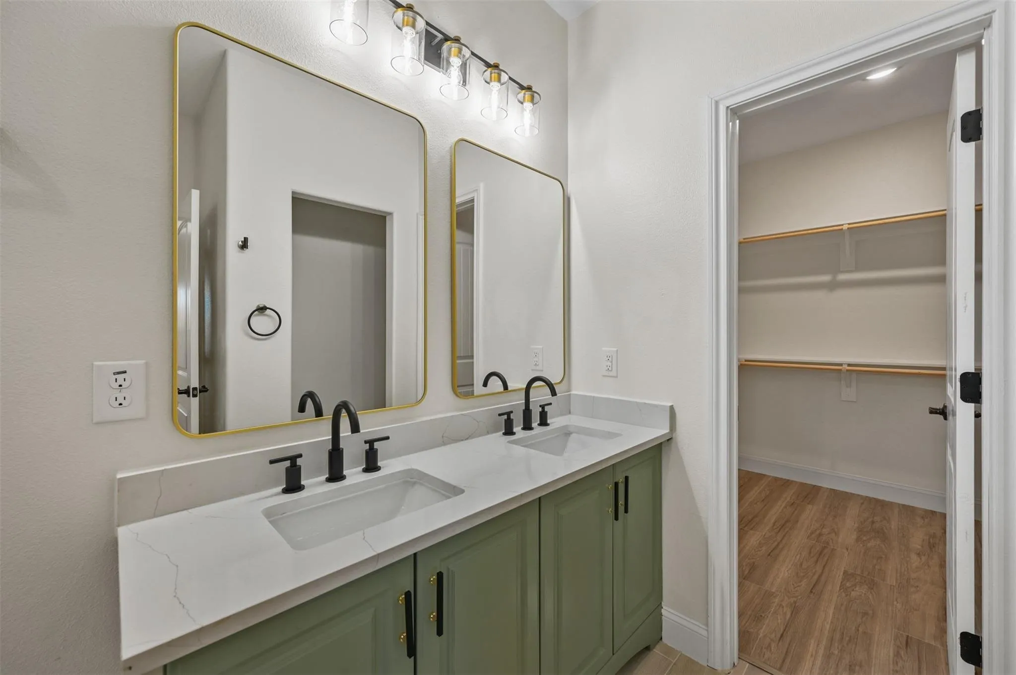 Bathroom vanity featuring dual rectangular sinks, matte black fixtures, a white stone countertop, and green cabinetry