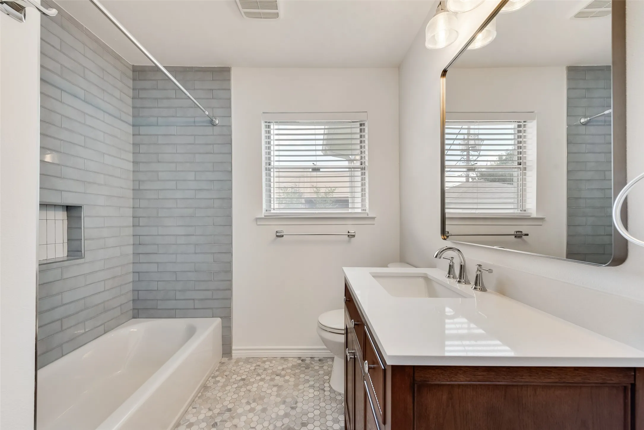 Bathroom featuring a white bathtub with light gray subway tile surround and integrated niche
