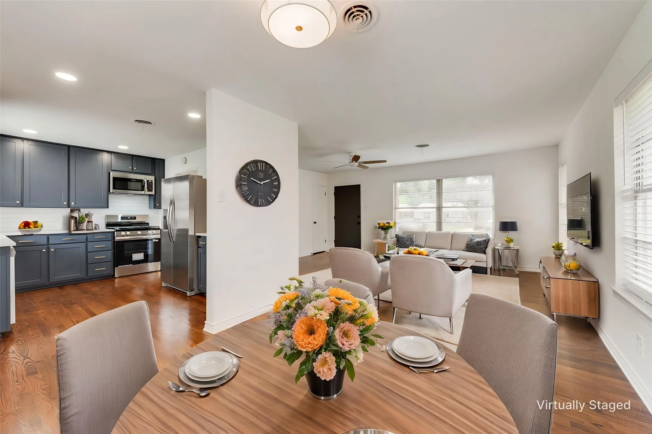 Open concept living area featuring wood-finish flooring, recessed lighting, and a kitchen with dark cabinetry and stainless steel appliances