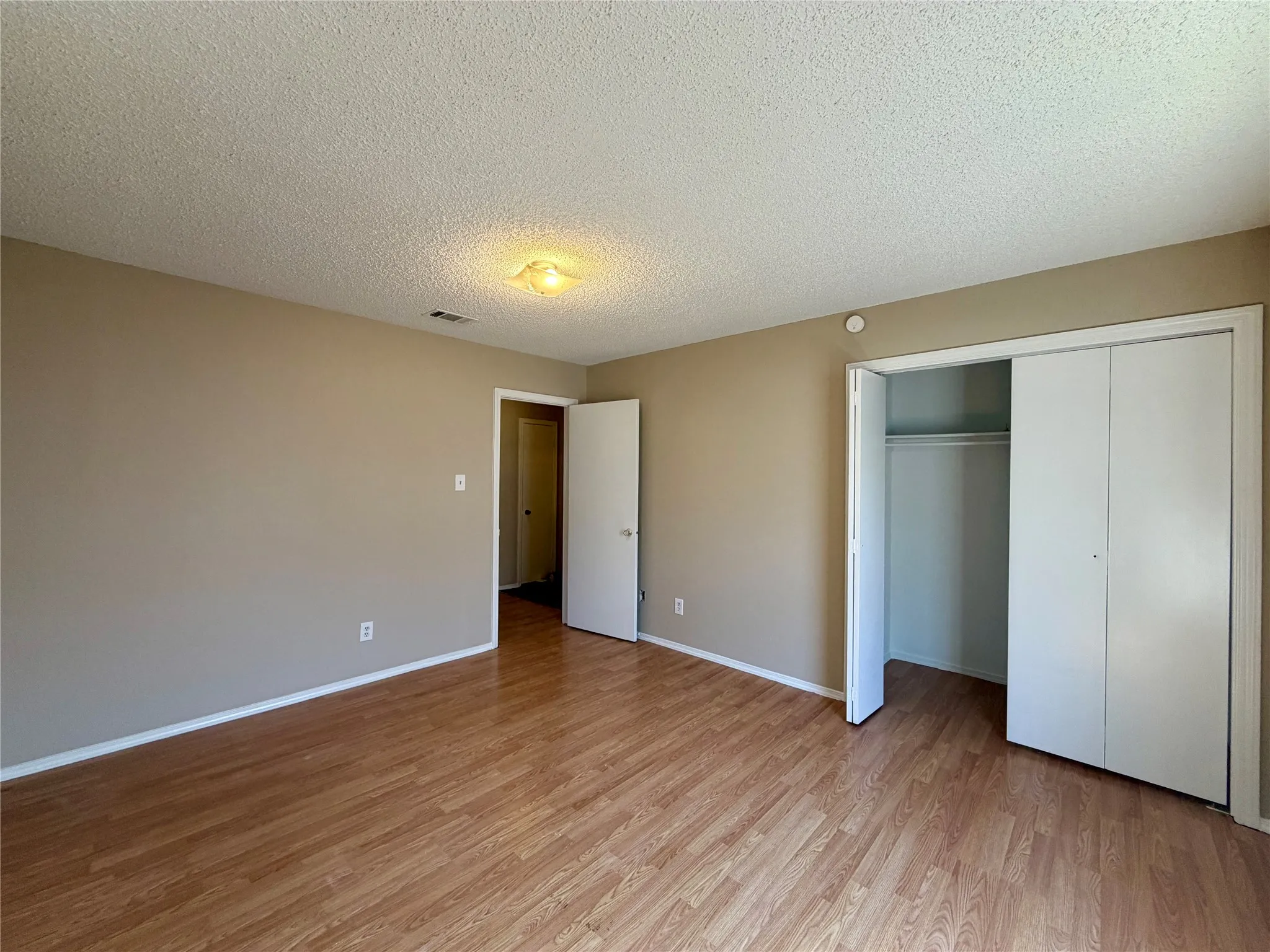 Wood-finish flooring, neutral wall paint, and a built-in closet with bi-fold doors