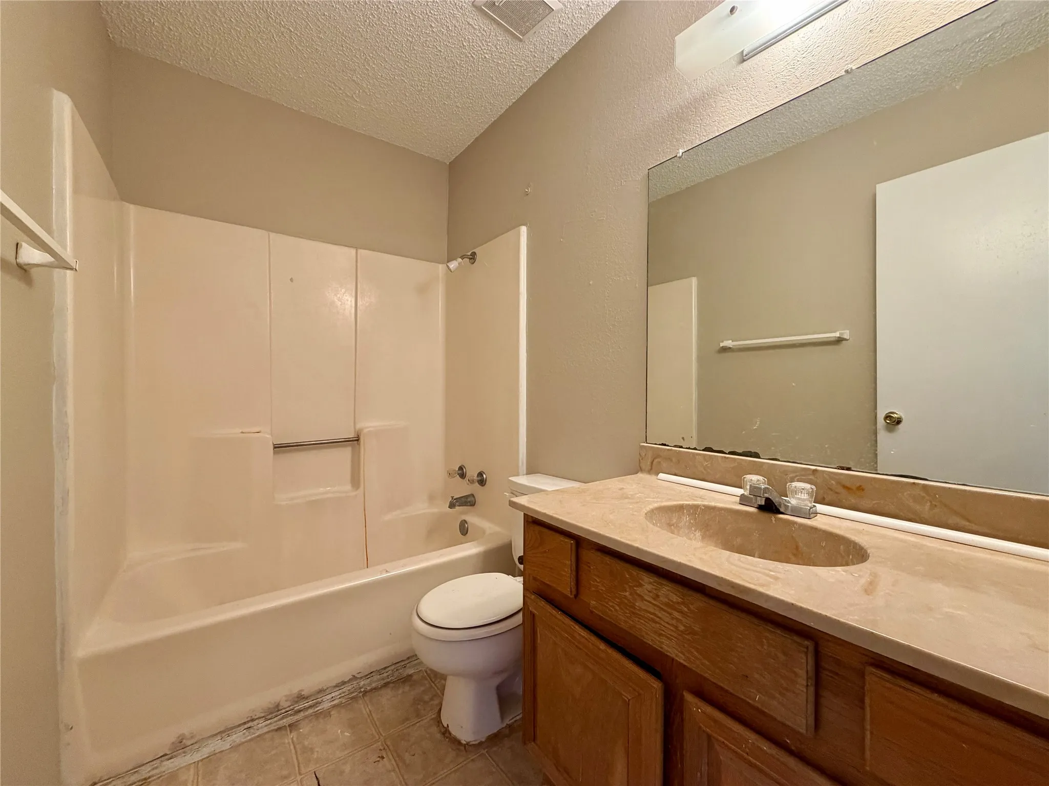 Bathroom featuring a built-in vanity with an integrated sink, a large wall-mounted mirror, and a combination bathtub/shower unit