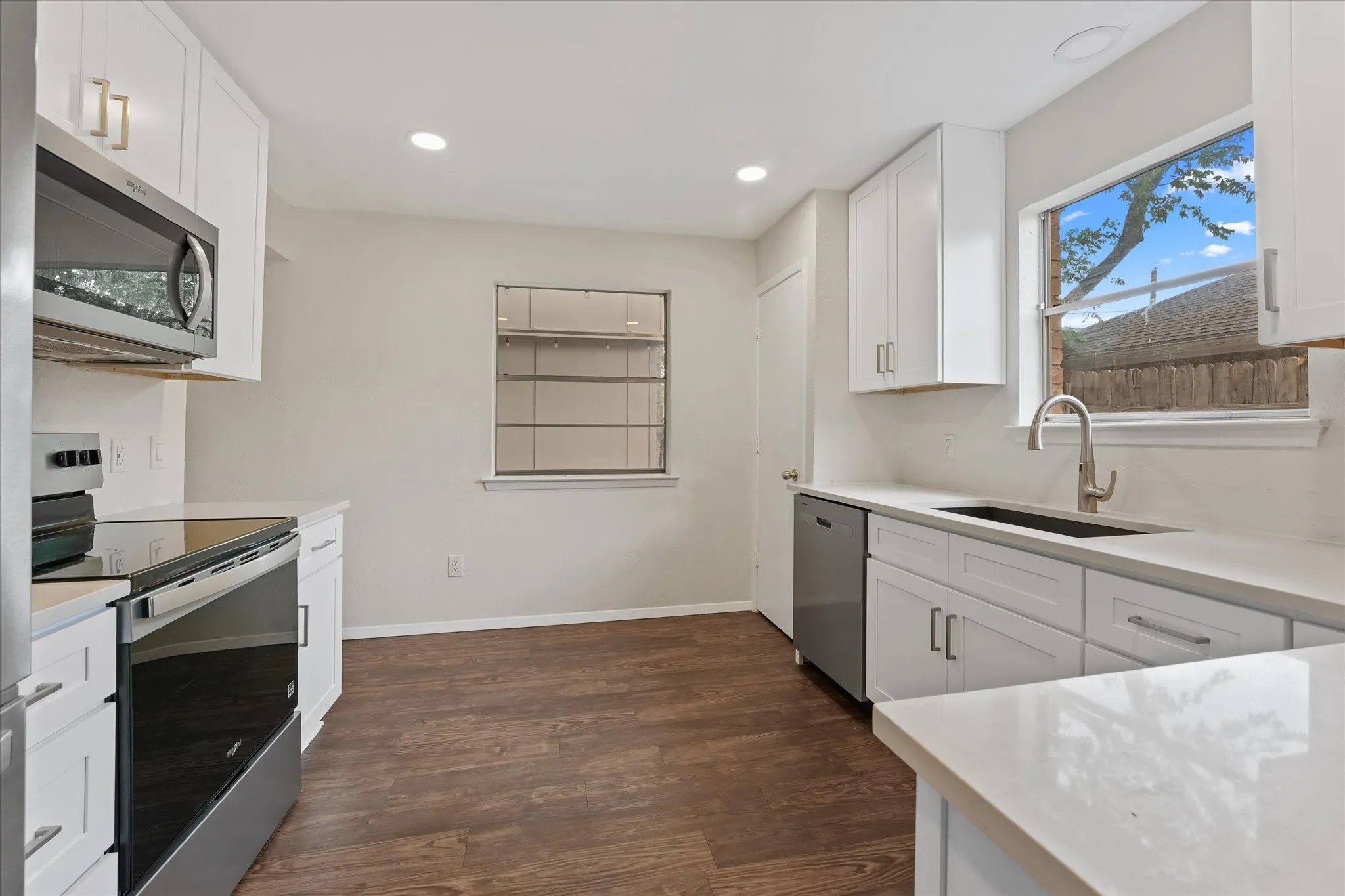 Kitchen featuring white cabinetry, light countertops, wood-finish flooring, stainless steel appliances, and recessed lighting