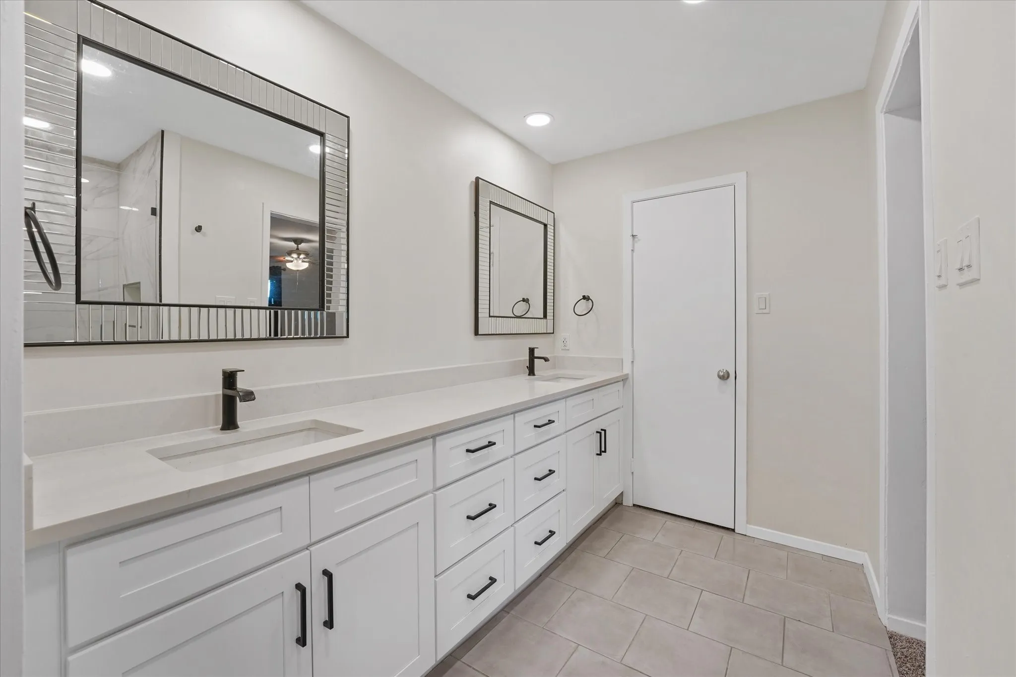 Dual vanity with white cabinetry and matte black hardware, featuring integrated sinks and light-toned countertops