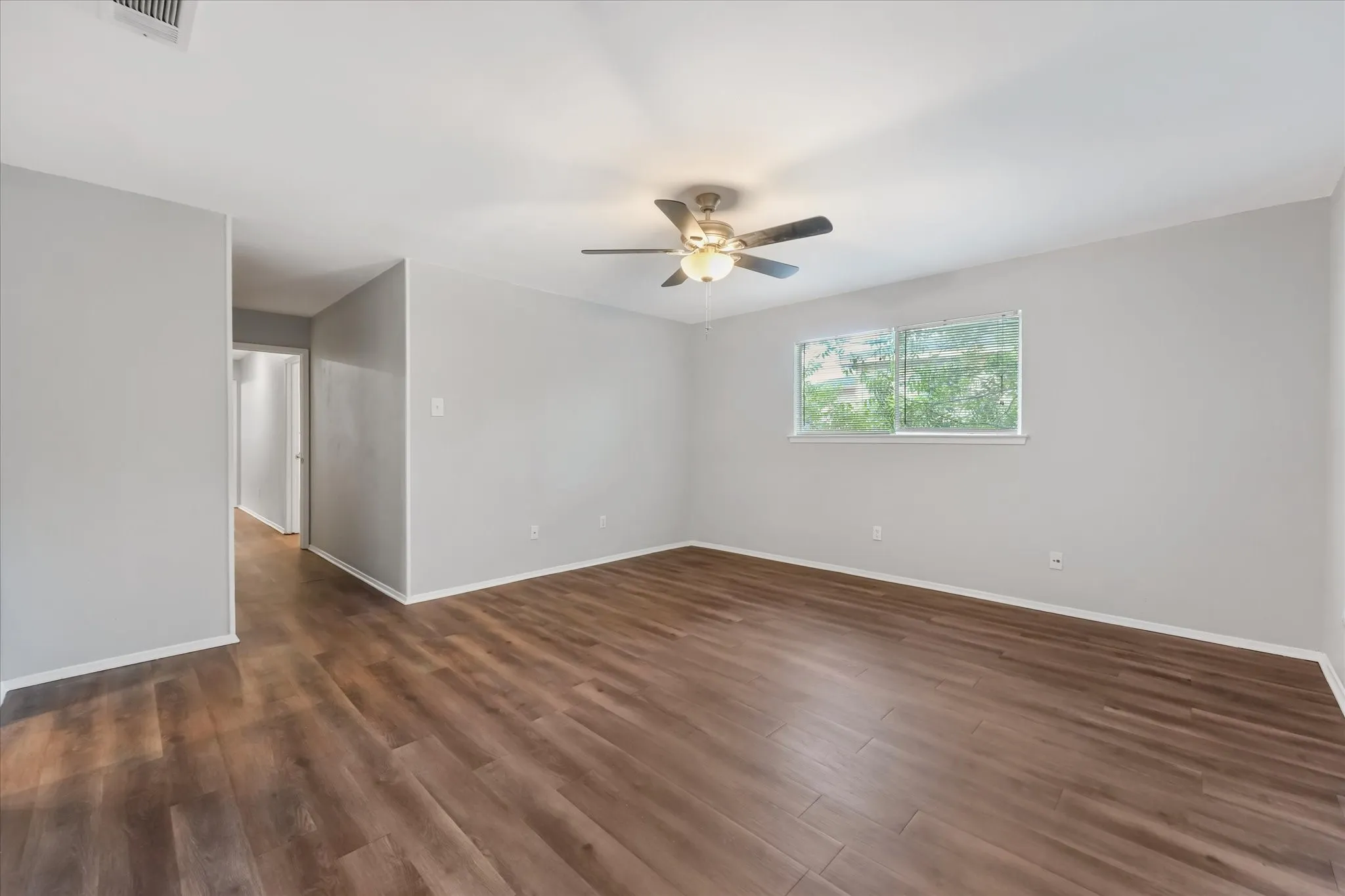 Spacious primary bedroom featuring wood-finish flooring and a neutral color palette