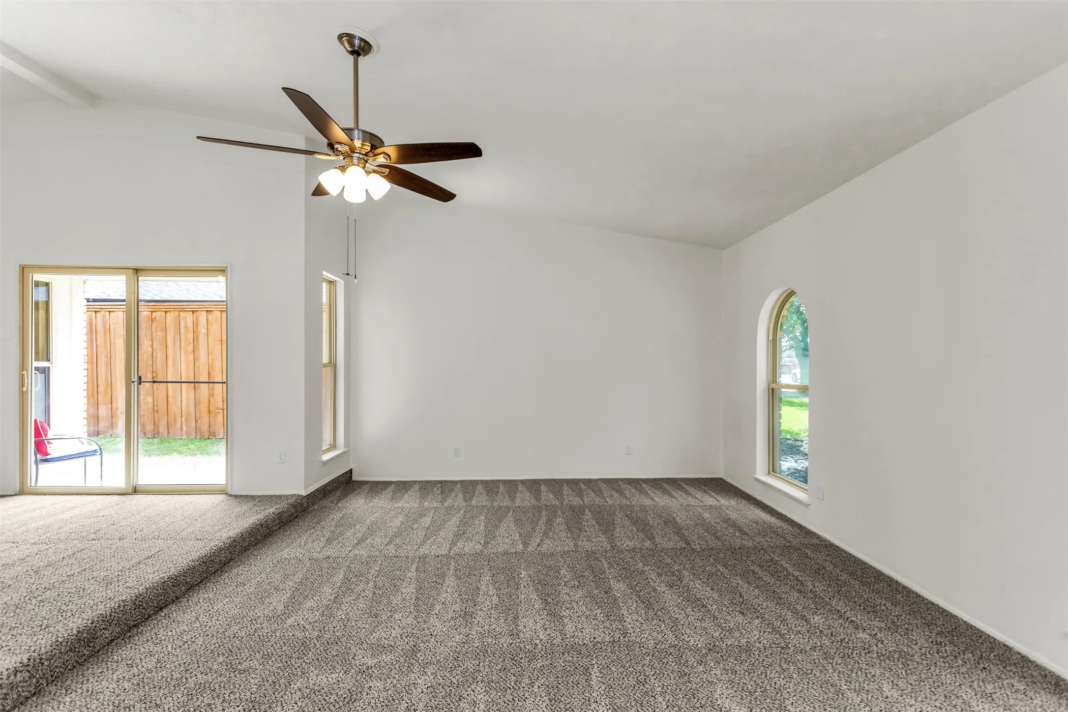 Spacious room with vaulted ceilings and patterned carpet flooring