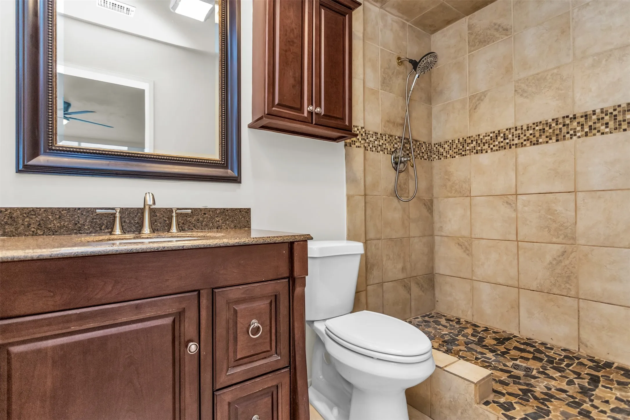 Full bathroom featuring a dark wood-finish vanity with a stone countertop, an integrated sink, and a framed mirror