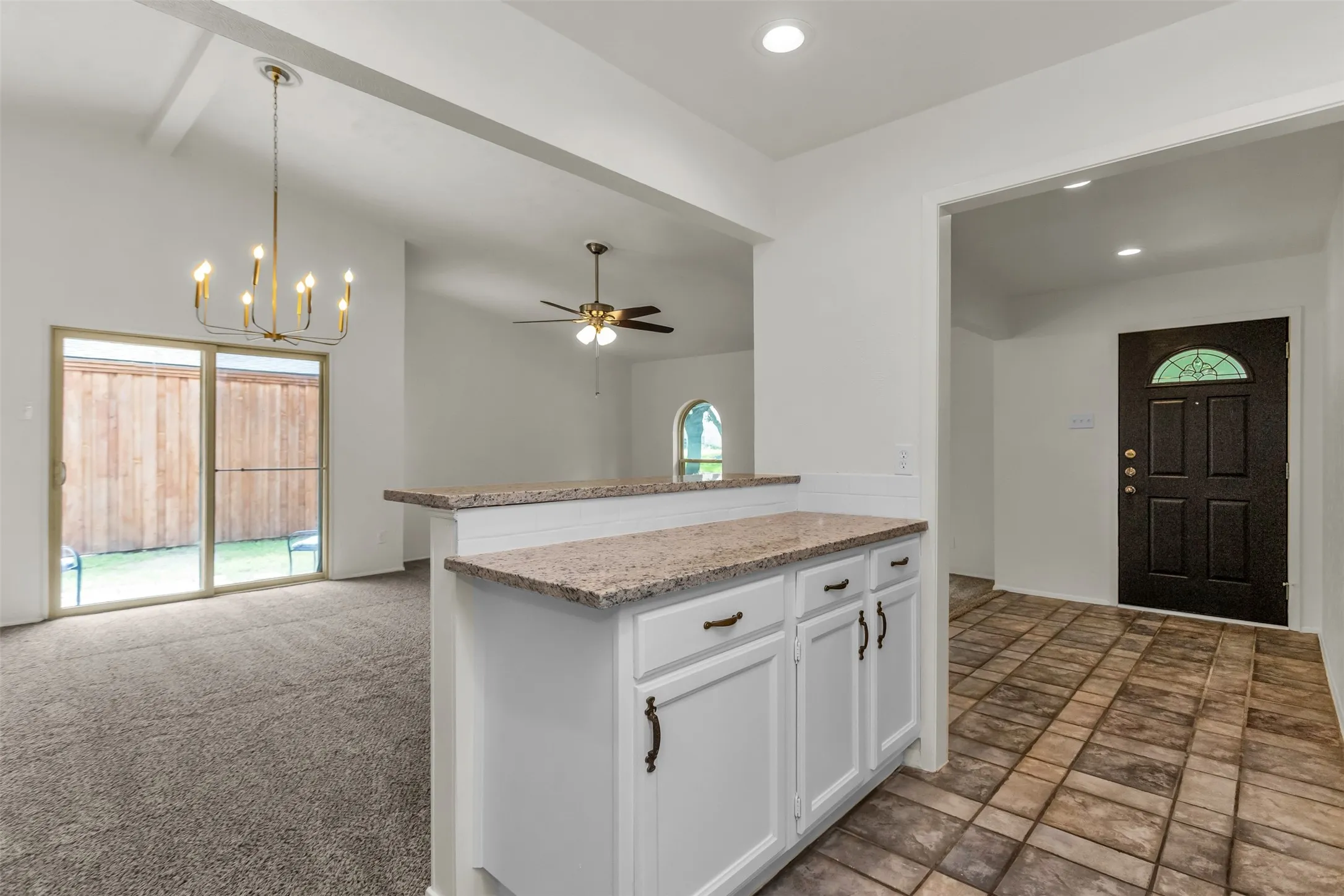 Open-concept living area with a wet-bar featuring granite-finish countertops and white cabinetry