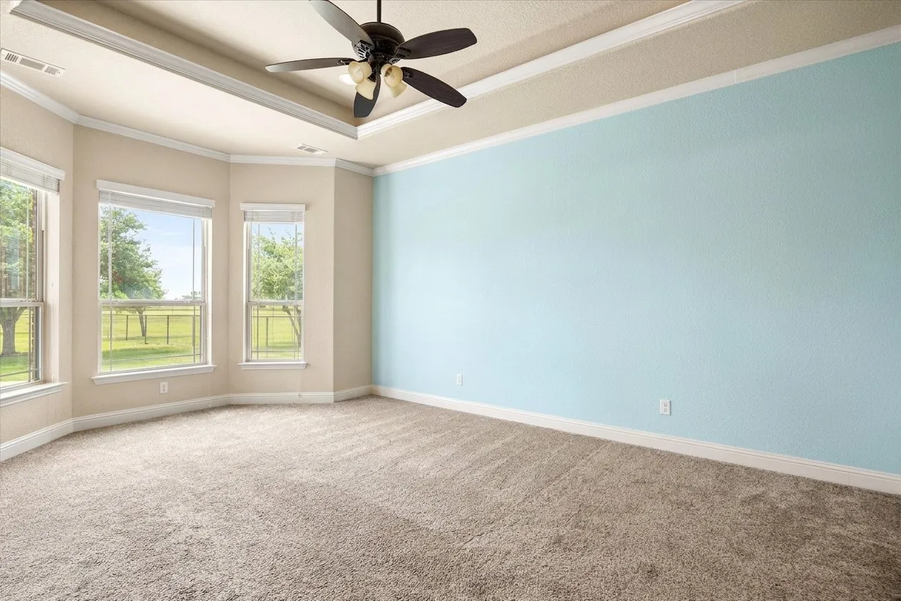 Large primary bedroom with bay windows and access to back patio.