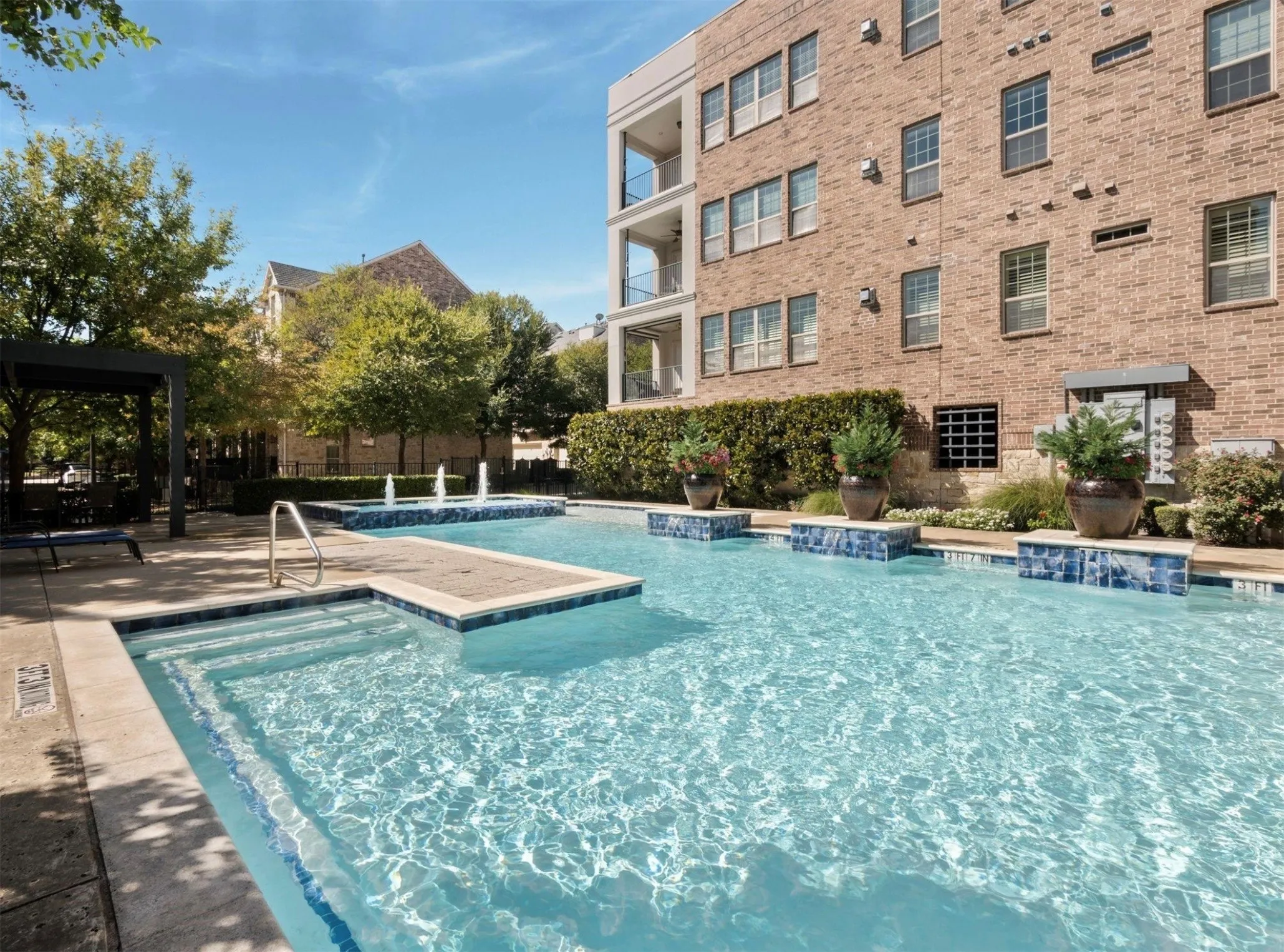 Outdoor swimming pool featuring a tiled spa, integrated fountains, and surrounding hardscaping