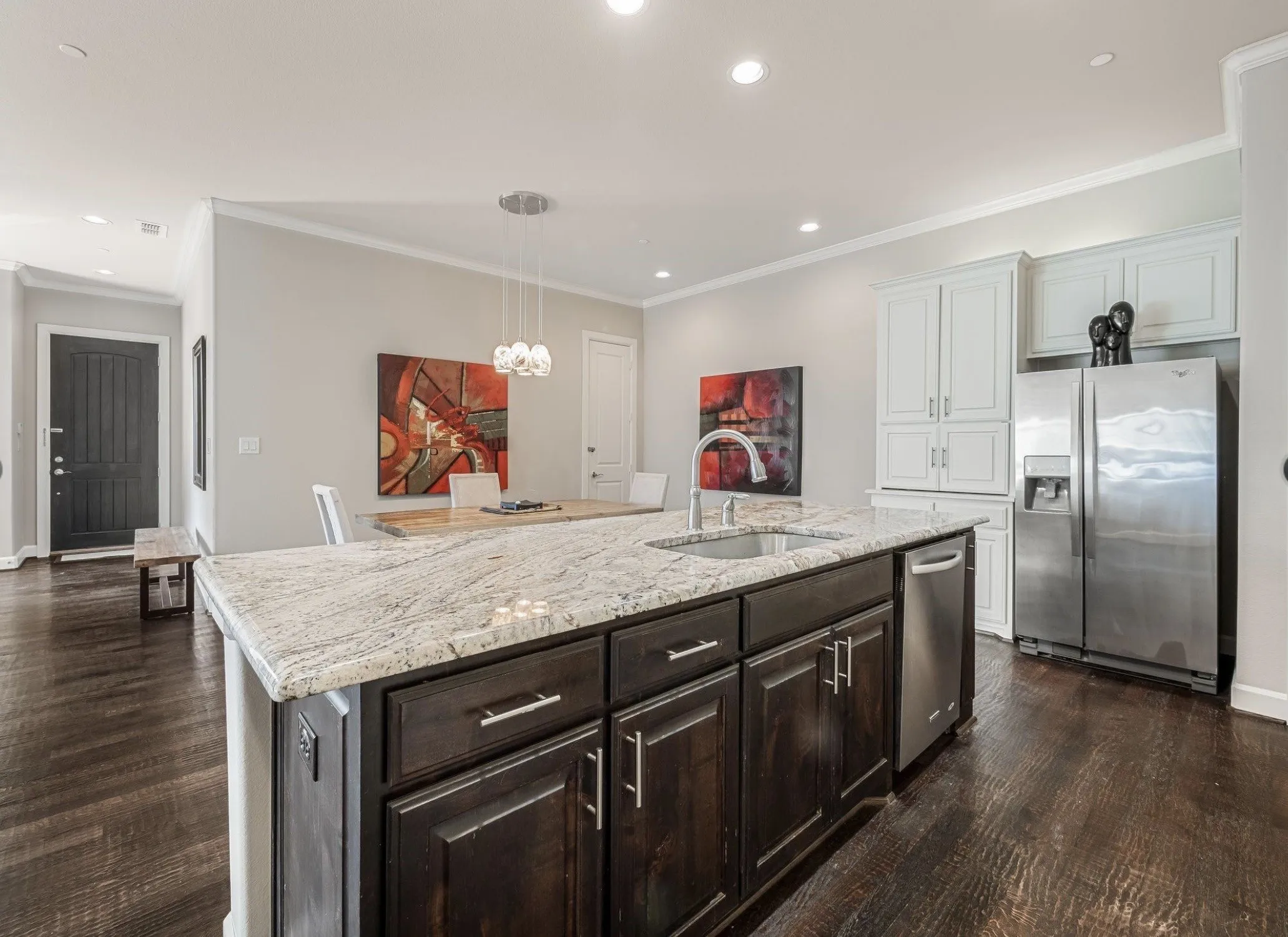 Kitchen island featuring a light-toned countertop, integrated sink with a gooseneck faucet, and dark-finish cabinetry