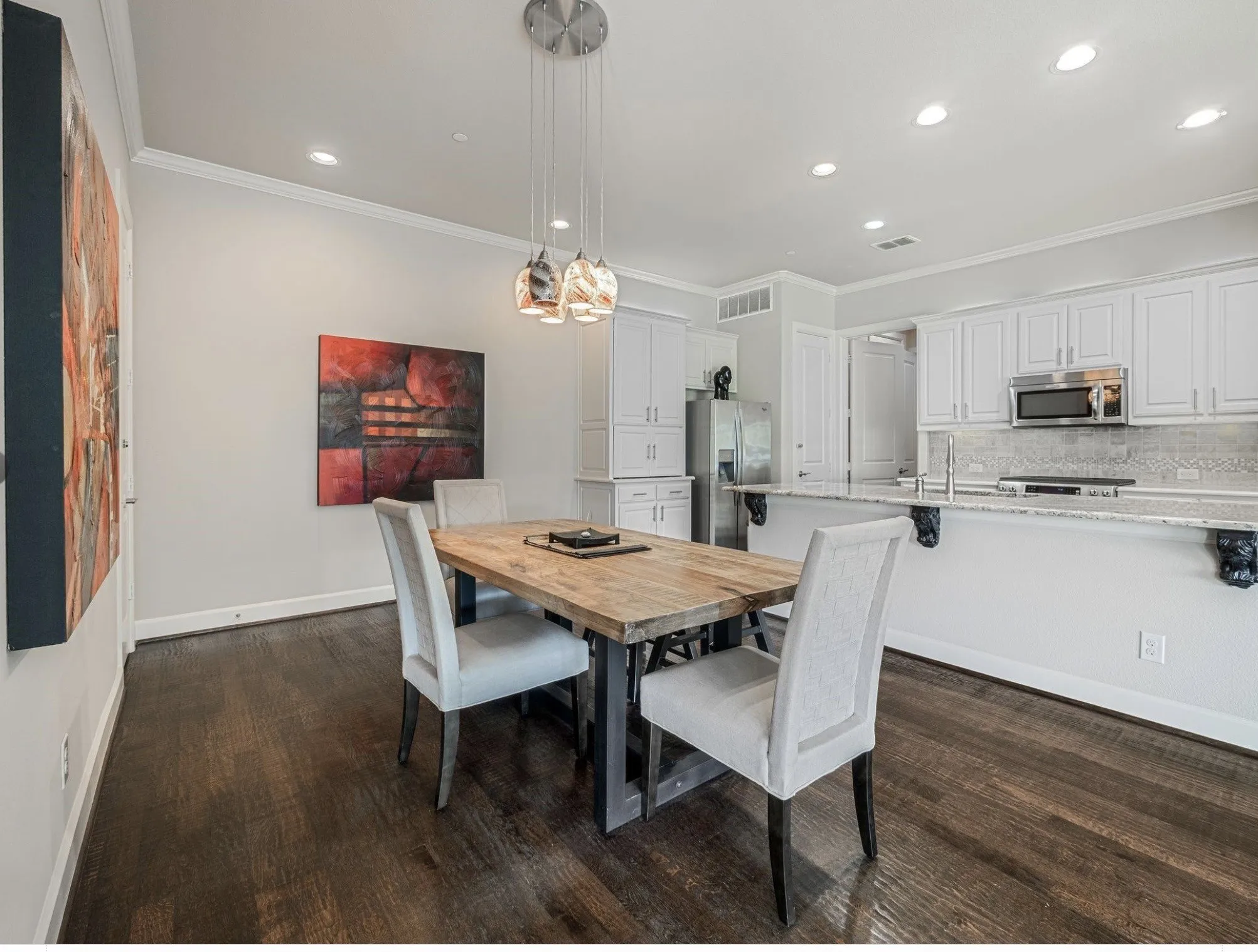 Open-concept dining area featuring dark wood-finish flooring, recessed lighting, and crown molding