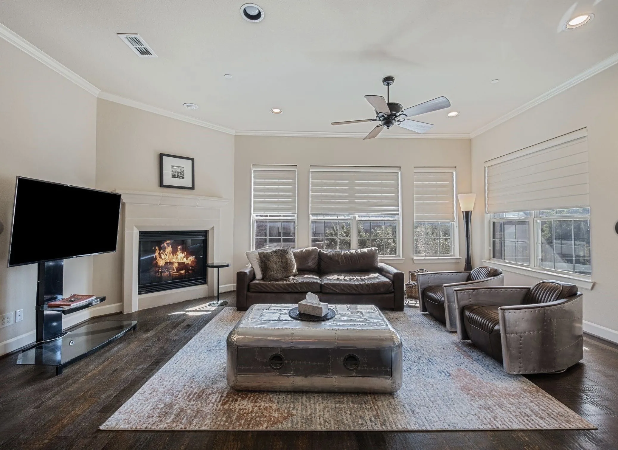 Living area featuring wood-finish flooring, a white mantel fireplace, and multiple windows with blinds