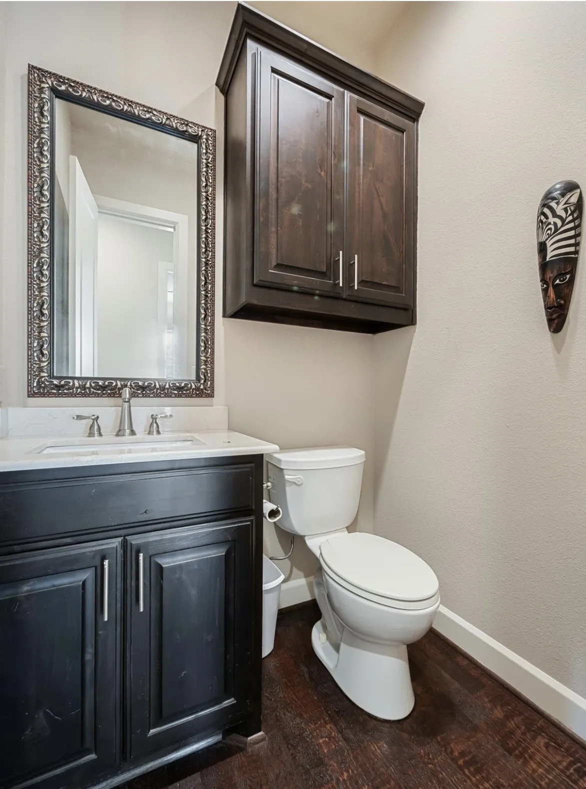 Bathroom featuring dark wood-finish flooring, a white toilet, and a vanity with a white countertop and dark cabinetry