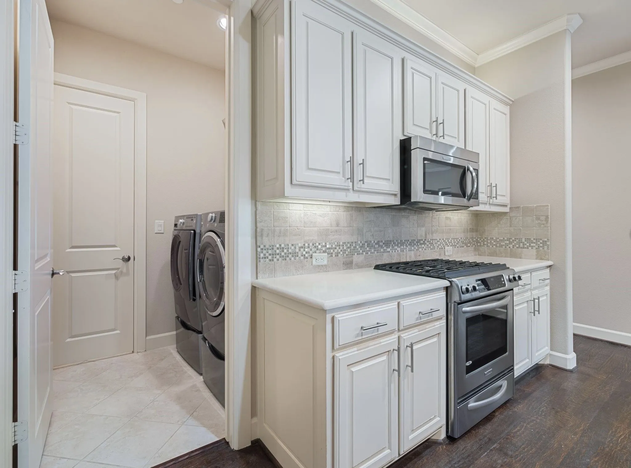 Kitchen area featuring white cabinetry, stainless steel microwave, gas range, and stone countertops