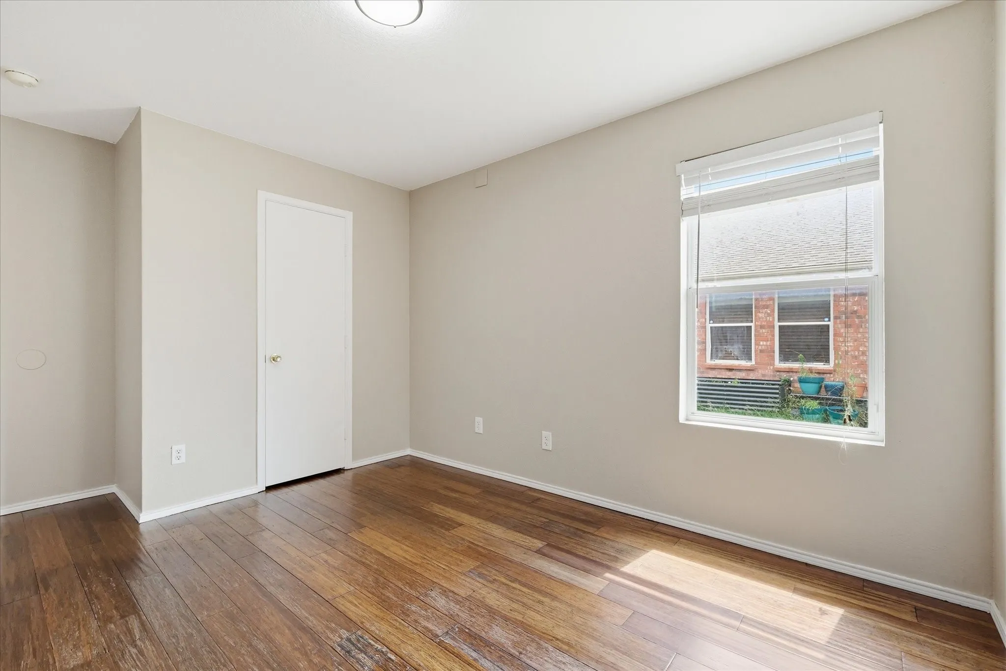 Room featuring wood-finish flooring, a single window with blinds, and light-toned walls