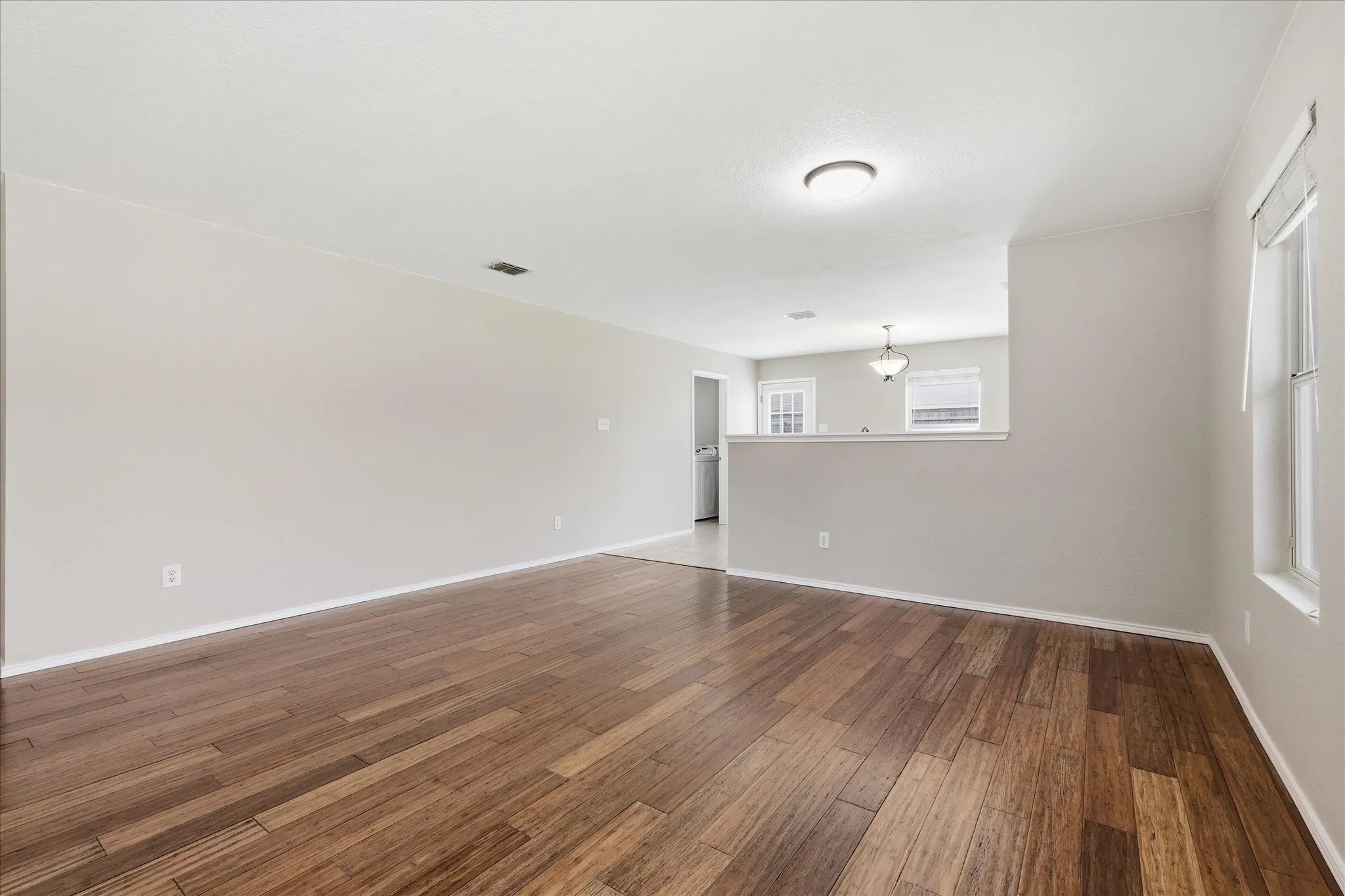 Expansive living area featuring wide plank wood-finish flooring, a neutral wall palette, and recessed lighting