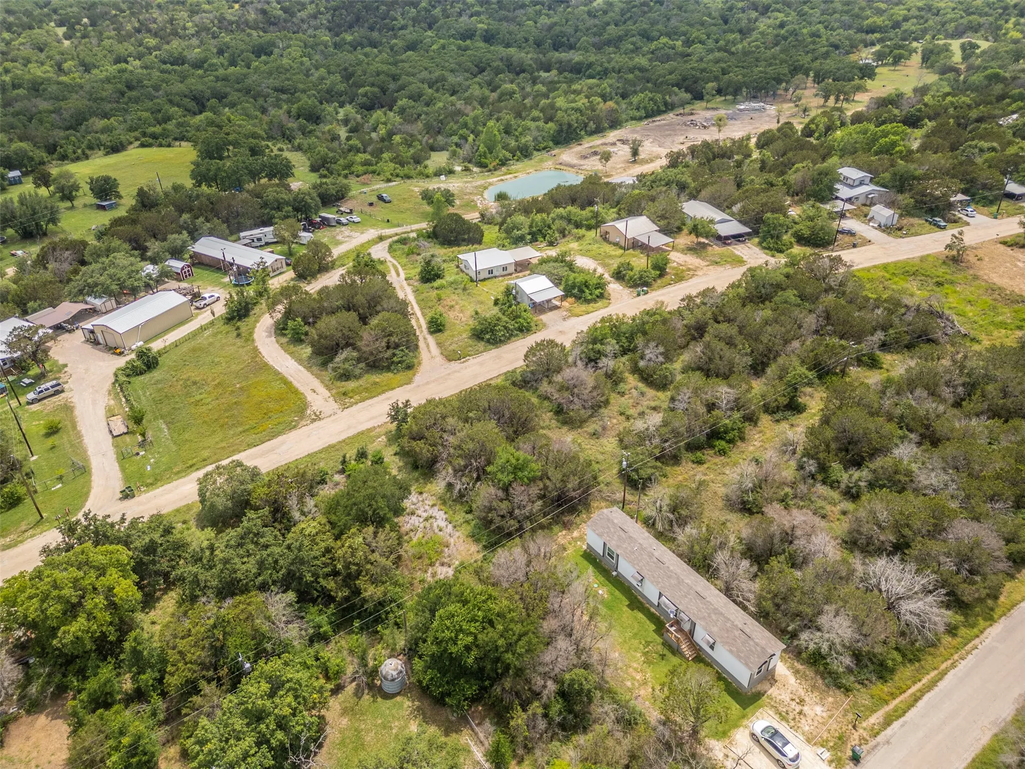 Expansive property featuring a manufactured home, several outbuildings, and a natural pond