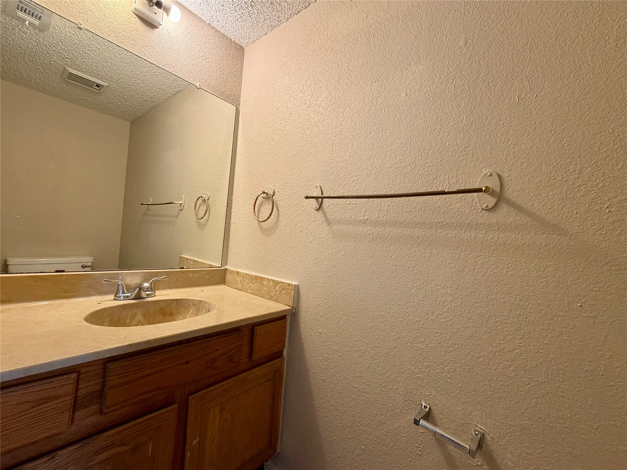 Wood-finish vanity cabinetry with a light-colored countertop and an integrated sink basin