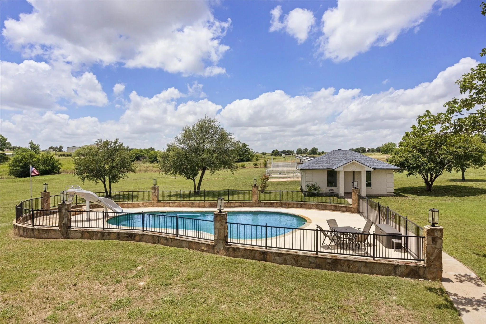 Deep Pool with Slide, Stone Surround, and Iron Fencing