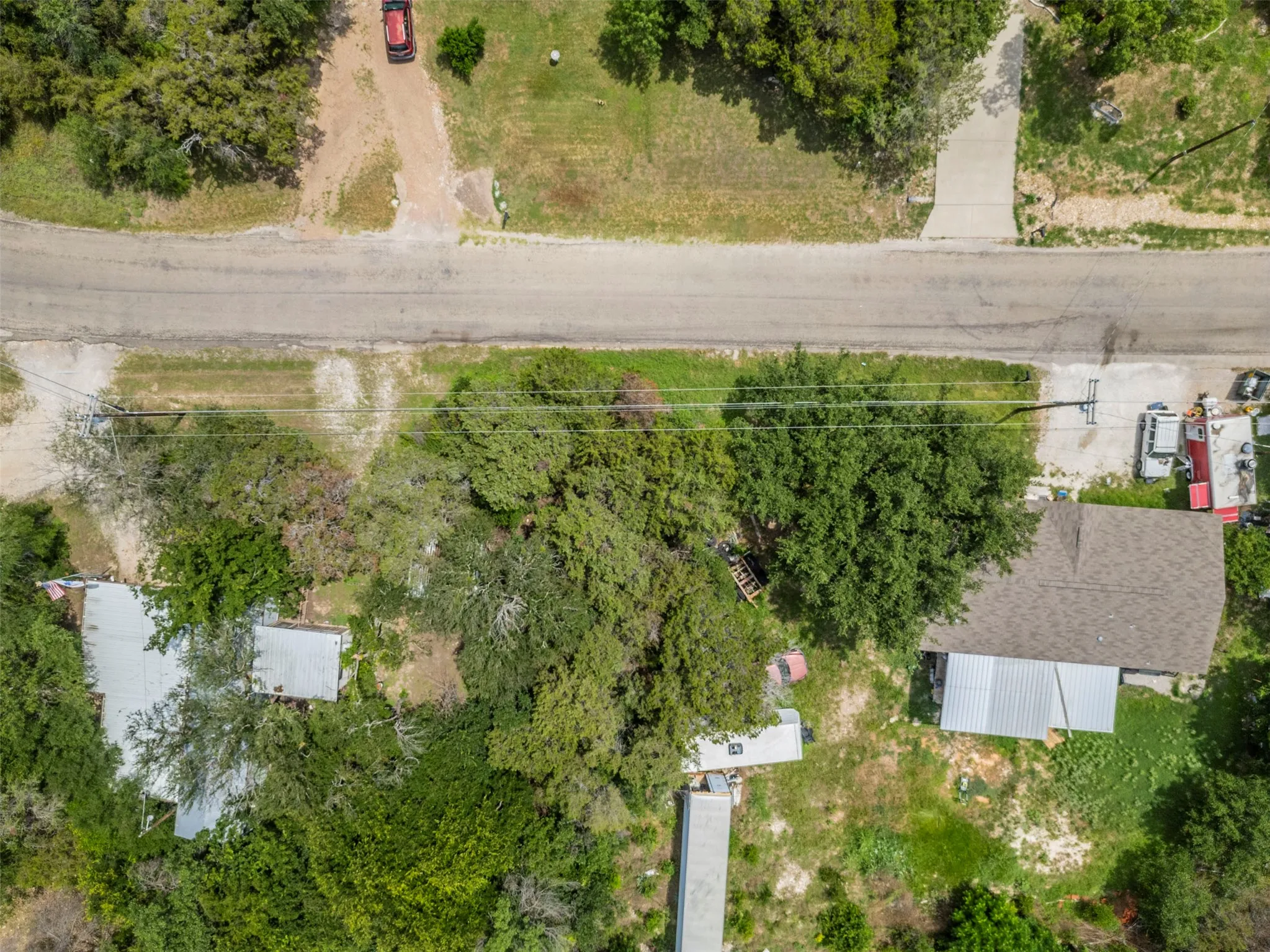 Aerial perspective showcasing a parcel with established trees and a residential structure featuring a shingle roof