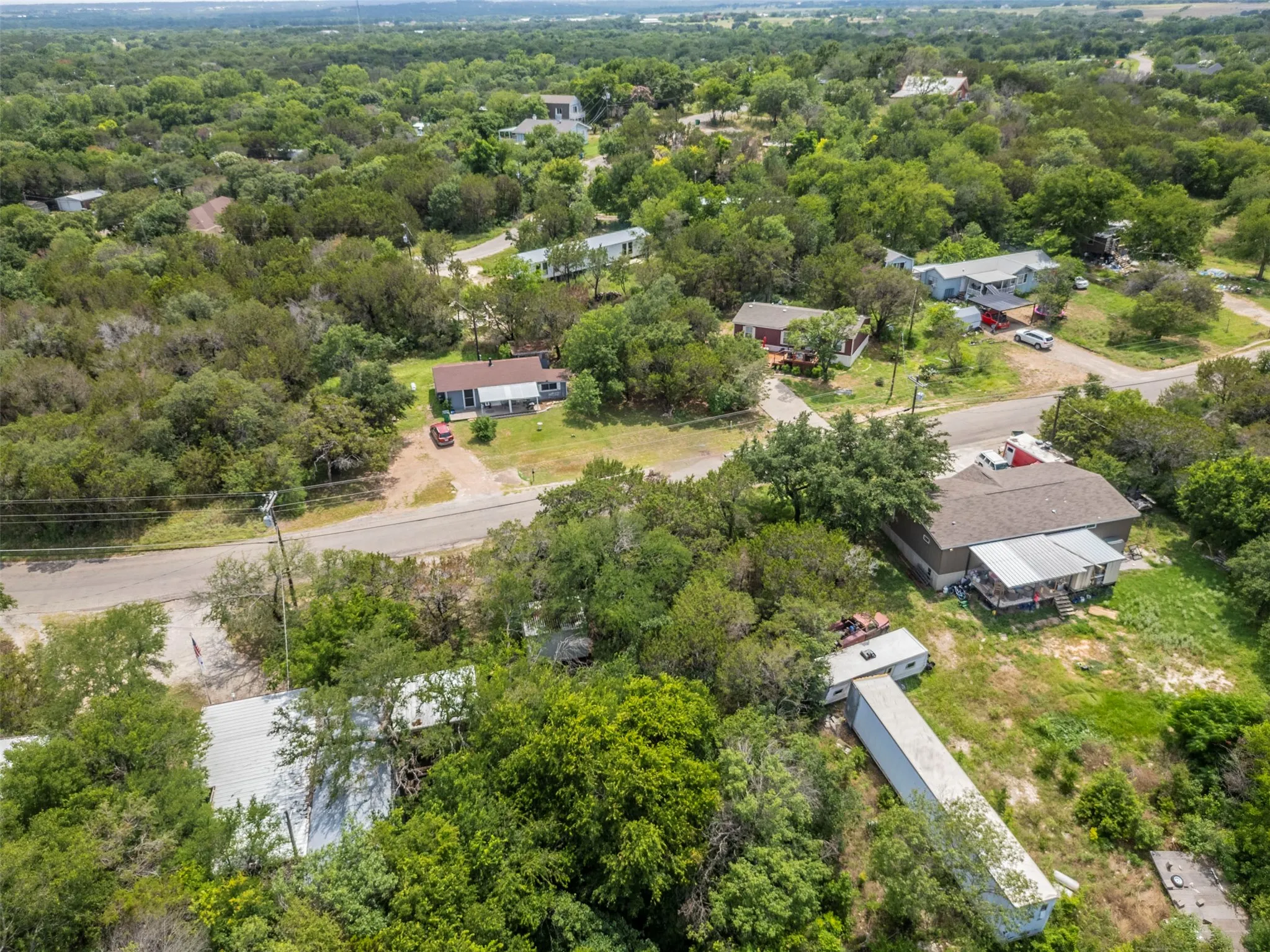 Aerial perspective of a verdant landscape featuring multiple residential structures and paved roads
