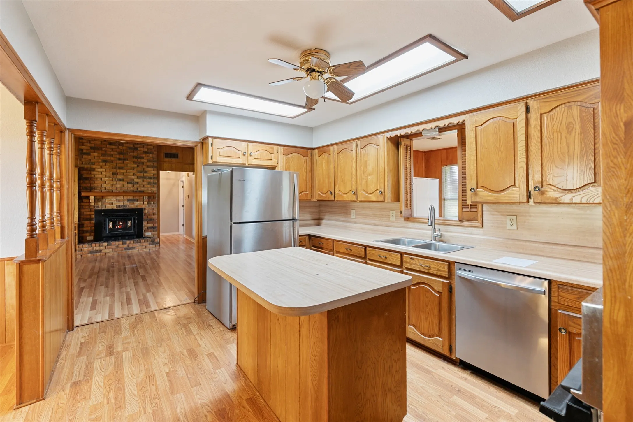 Kitchen featuring wood-finish cabinetry, stainless steel appliances, a center island with a laminate countertop, and wood-finish flooring
