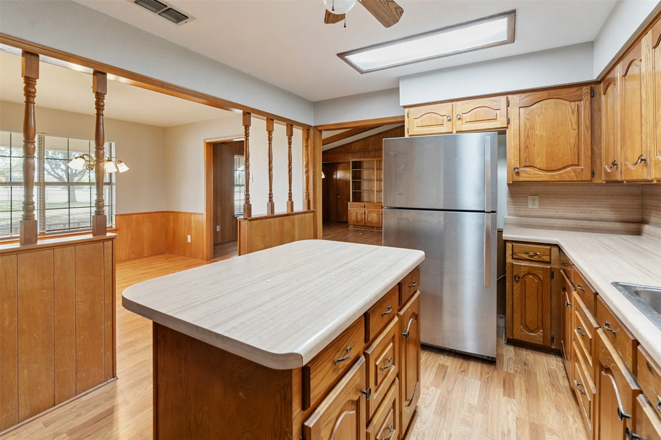 Kitchen featuring wood cabinetry, stainless steel refrigerator, and wood-finish flooring