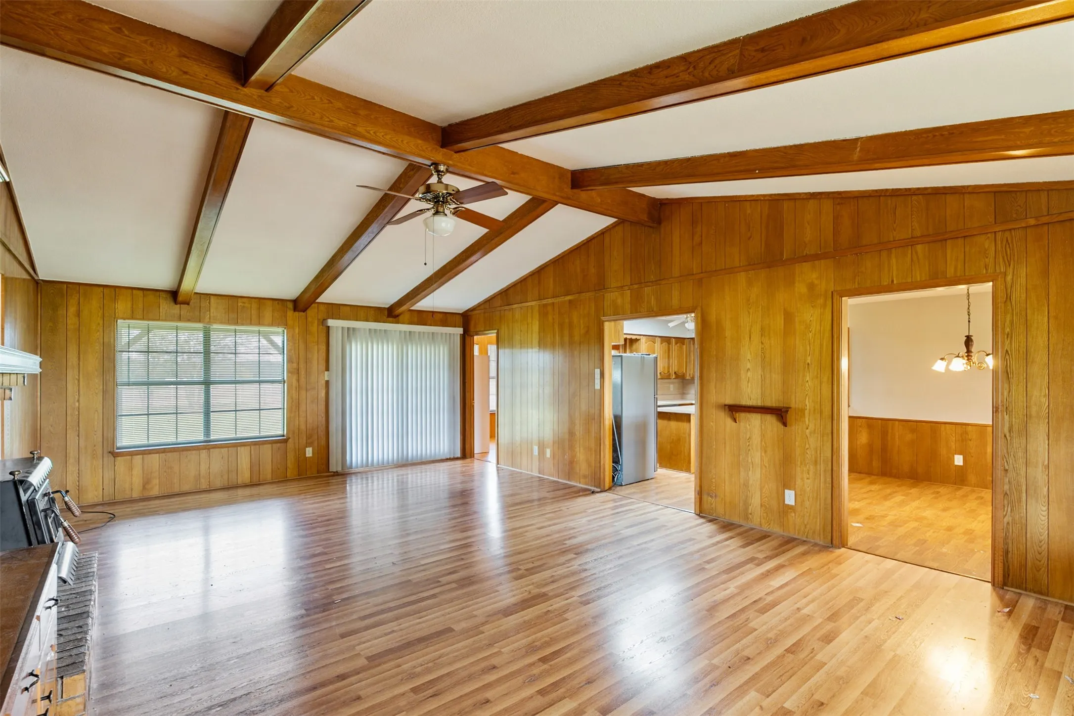 Vaulted ceiling with exposed wood beams, wood-finish flooring, and wood paneling throughout