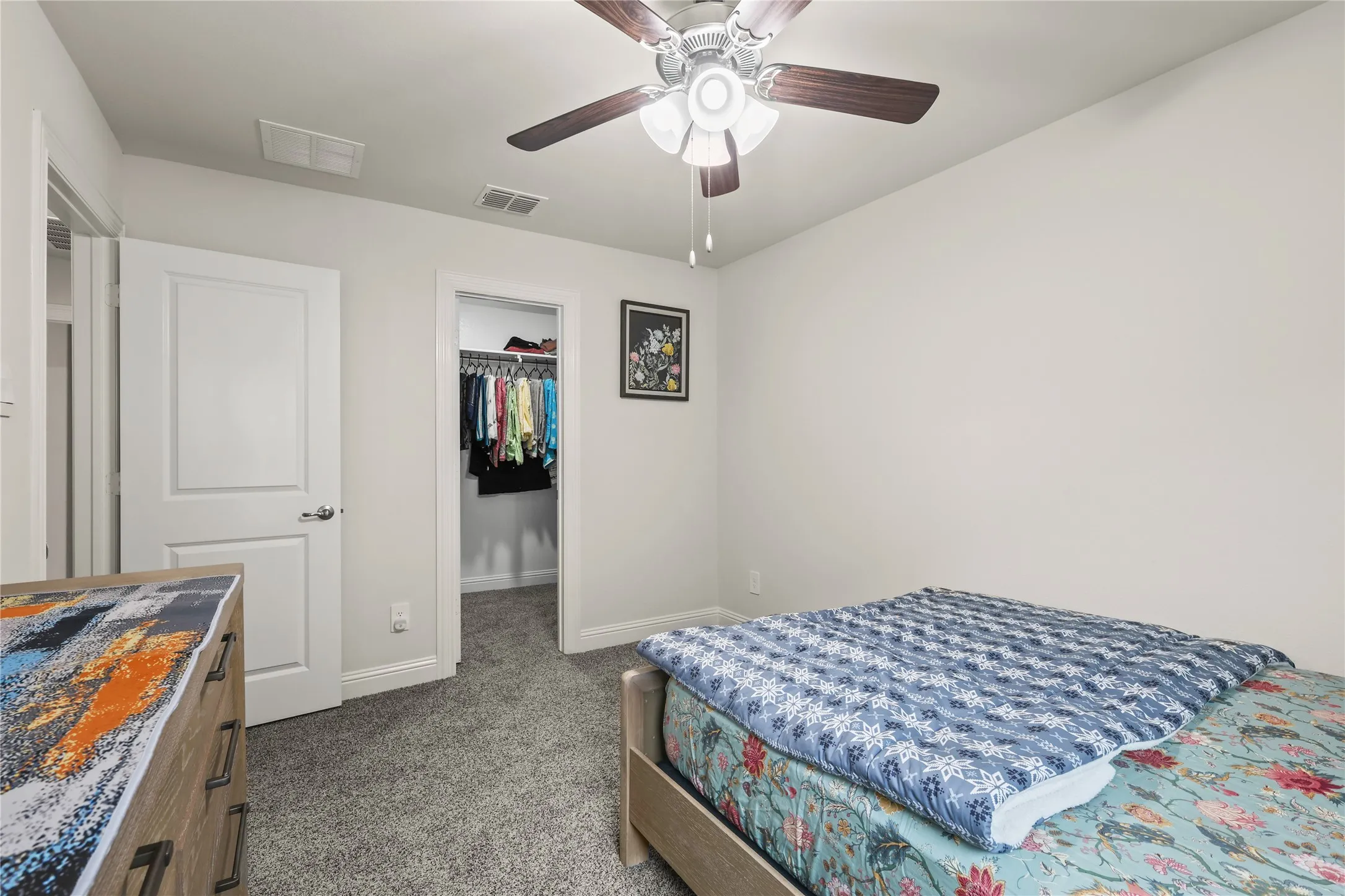 Room featuring neutral wall paint, gray carpeting, a ceiling fan with integrated lighting, a solid panel door, and a dedicated closet space