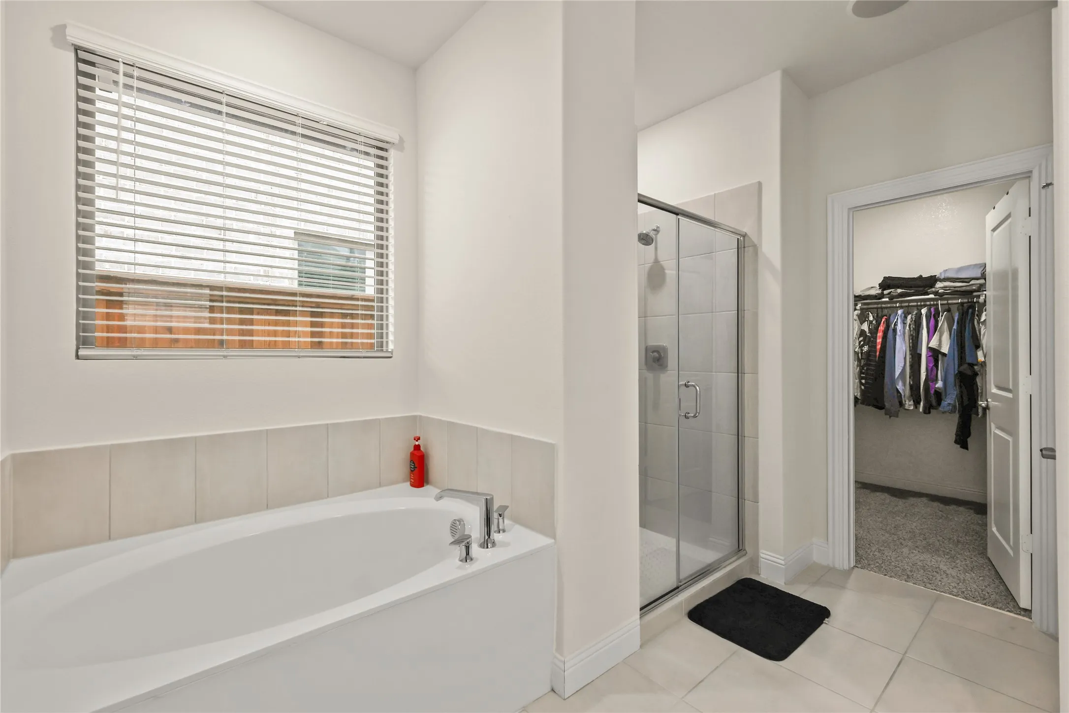 Bathroom featuring a built-in soaking tub with chrome fixtures, a separate glass-enclosed shower, and tile flooring