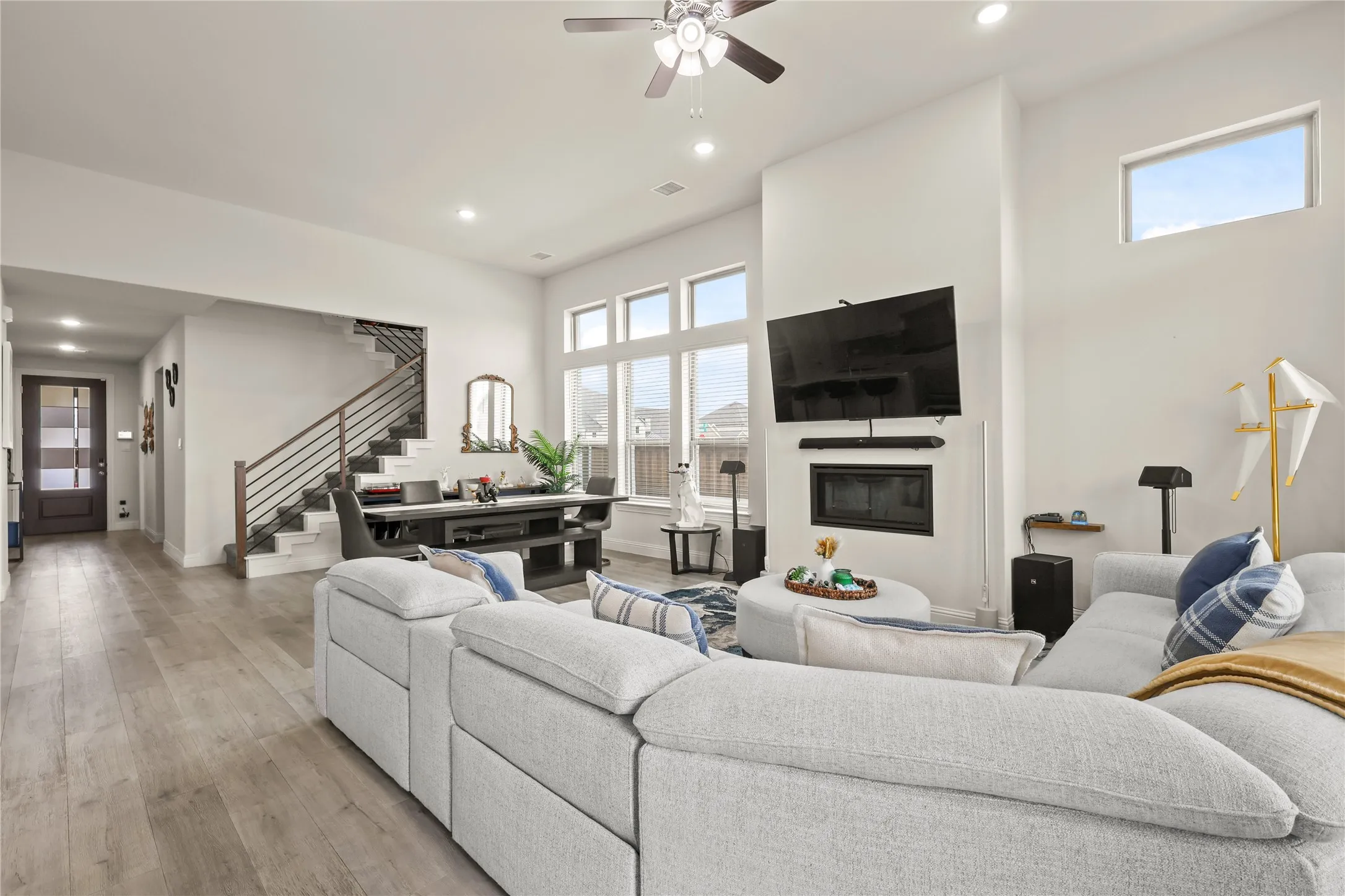 Spacious living area featuring high ceilings, large windows, a built-in fireplace, recessed lighting, and wood-finish flooring
