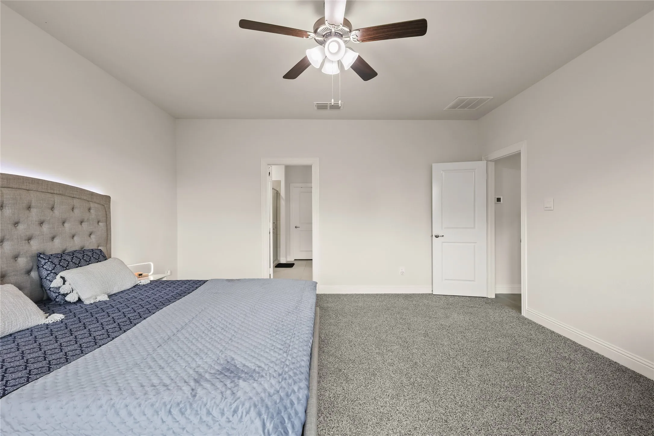 Spacious room featuring gray carpeting, white baseboards, and bright white walls