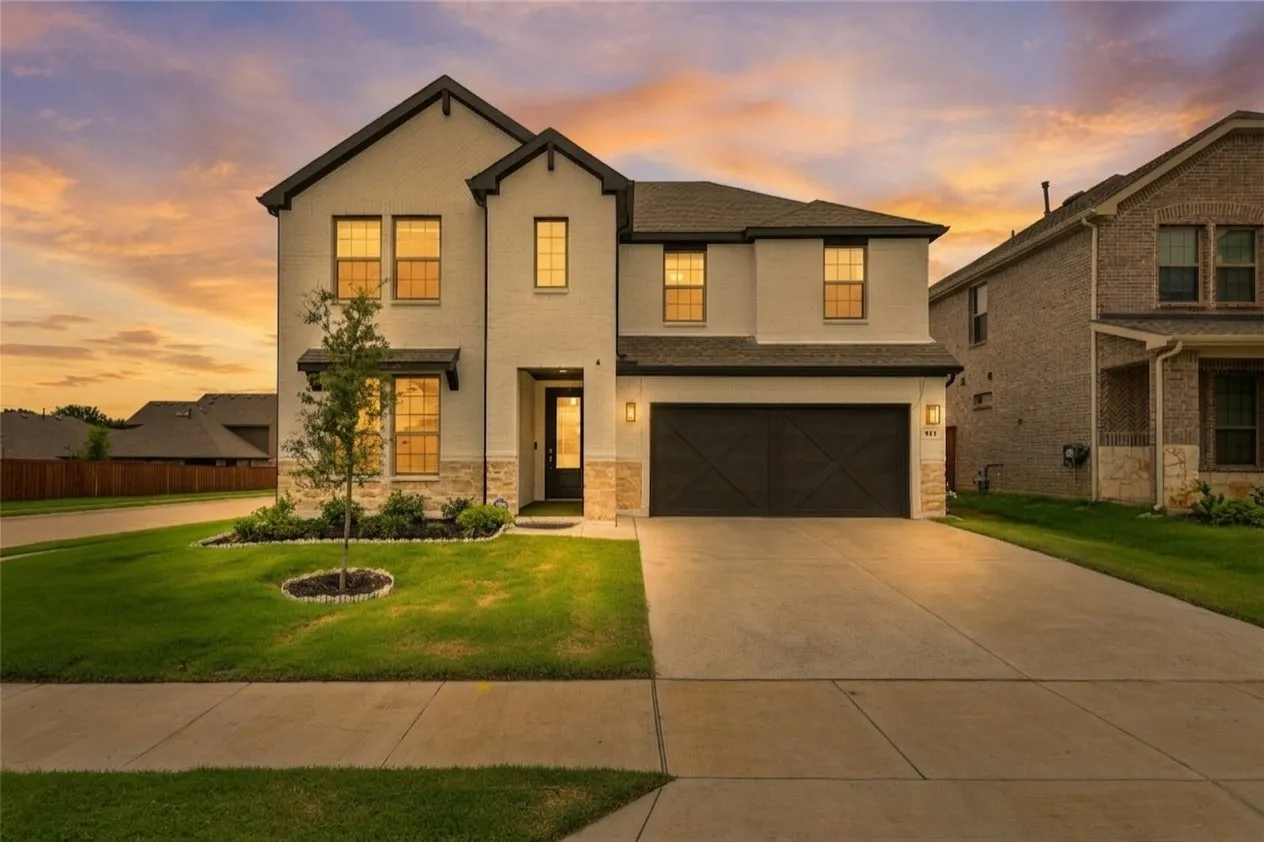 Two-story stucco and brick exterior featuring a dark gable roof and an attached two-car garage