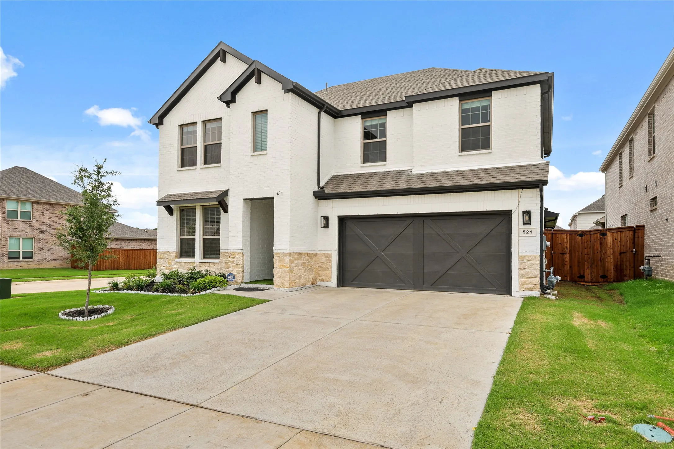 Two-story stucco residence with dark trim accents, a prominent two-car garage, and a concrete driveway