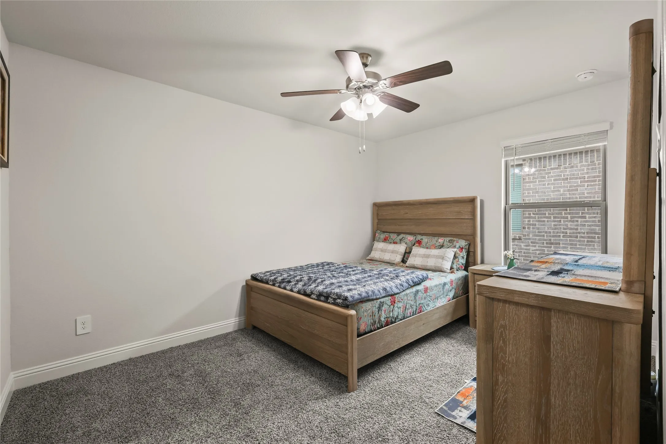 Neutral wall paint with white trim, gray carpet flooring, ceiling fan with light fixture, and a window with blinds
