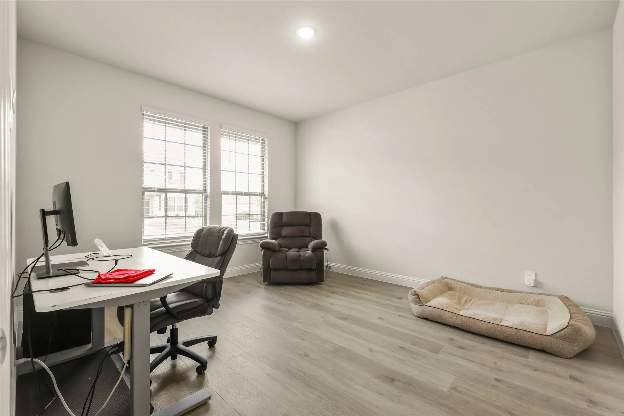 Spacious room featuring wood-finish flooring, white baseboards, and neutral wall paint