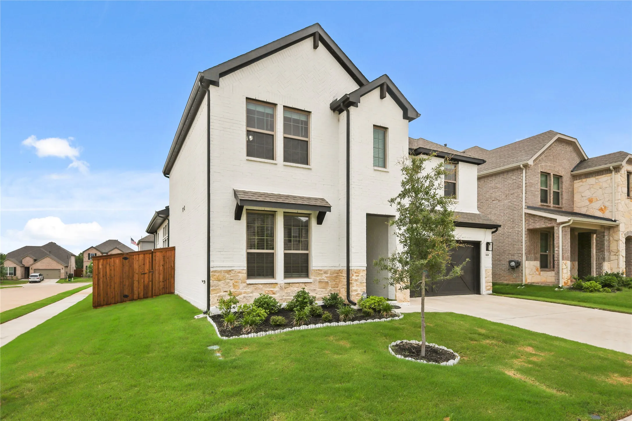 White brick exterior with black trim accents and a stone facade